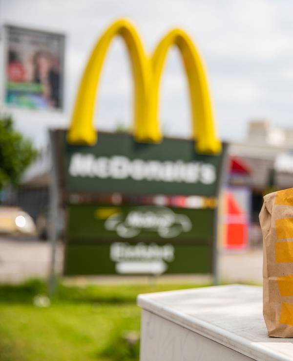 Eine McDonald's To-Go-Tüte und ein dazugehöriger To-Go-Becher stehen vor einer Tübinger McDonald's Filiale.