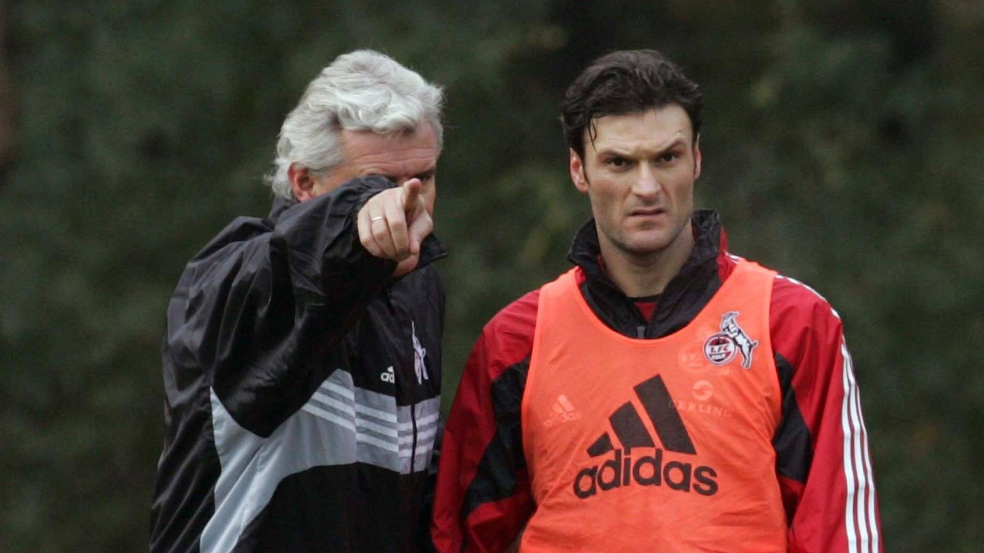 Uwe Rapolder zeigt Abwehr-Raubein Alpay im Training des 1. FC Köln am 22. November 2005 wo’s langgeht.