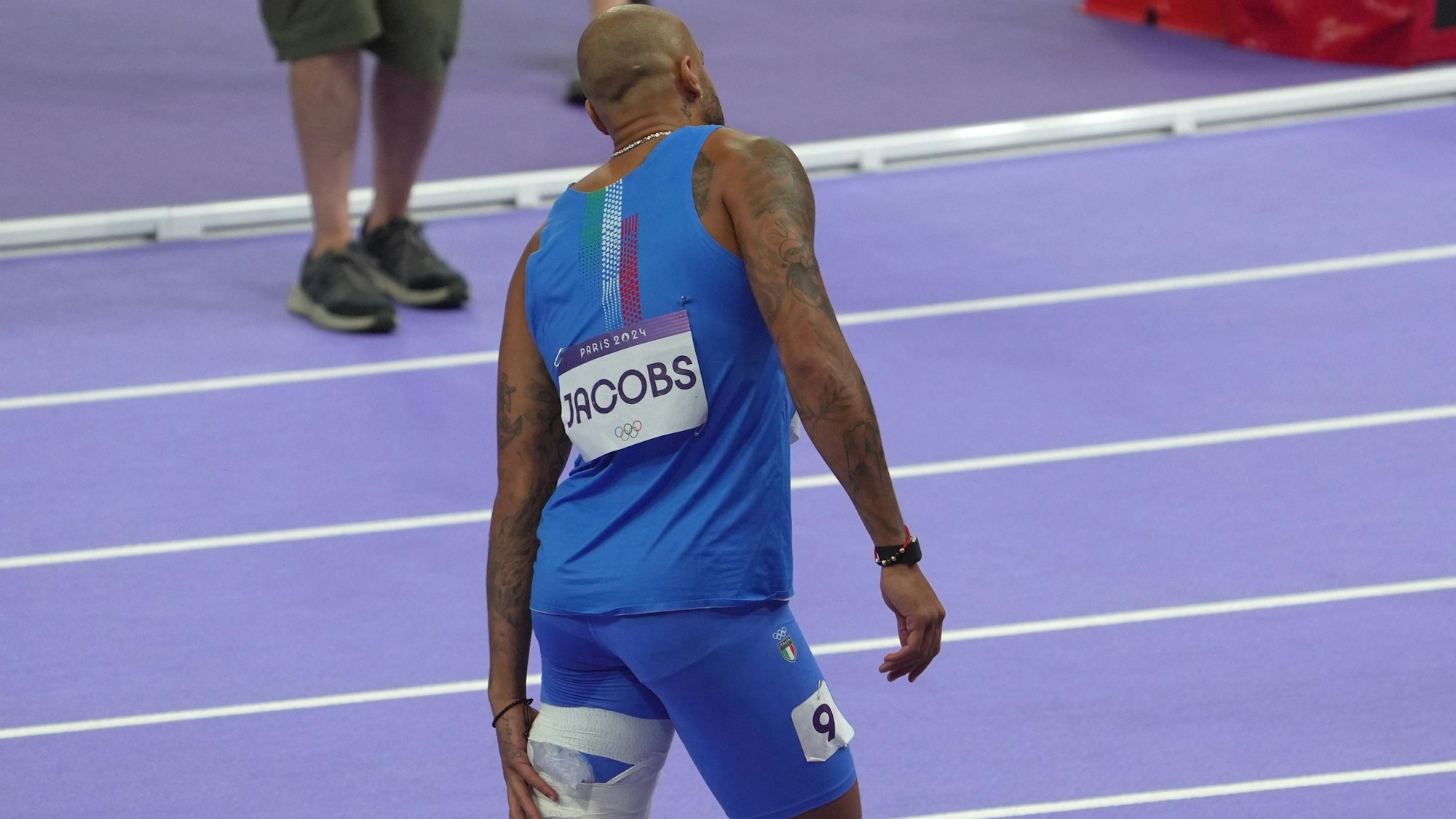 Marcell Jabocs humpelt mit dick bandagiertem und mit Eis gekühltem Oberschenkel nach dem Olympia-Rennen über 100 Meter aus dem Stadion.