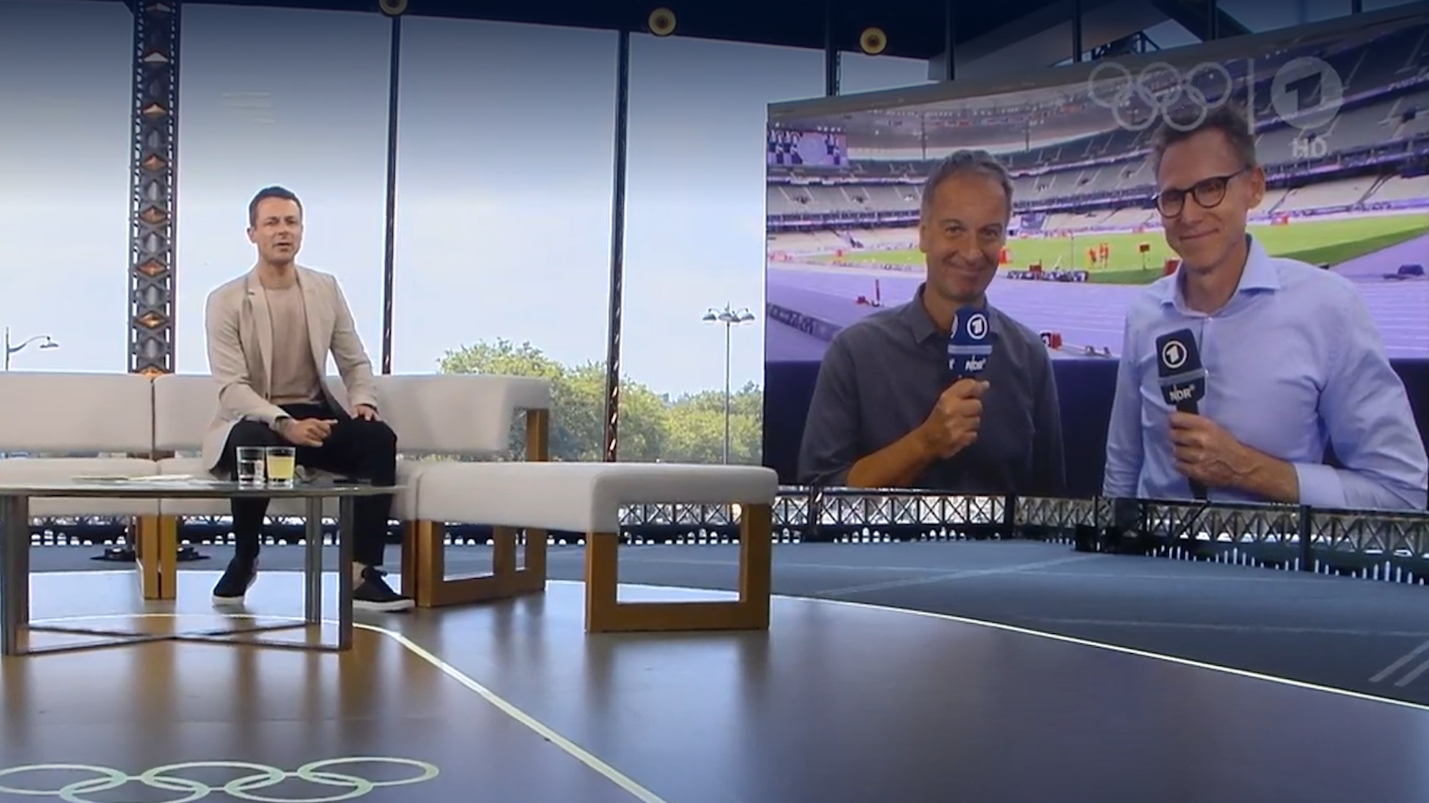 Alexander Bommes im Olympia-Studio der ARD, im Hintergrund sind Claus Lufen und Frank Busemann aus dem Stade de France zugeschaltet.