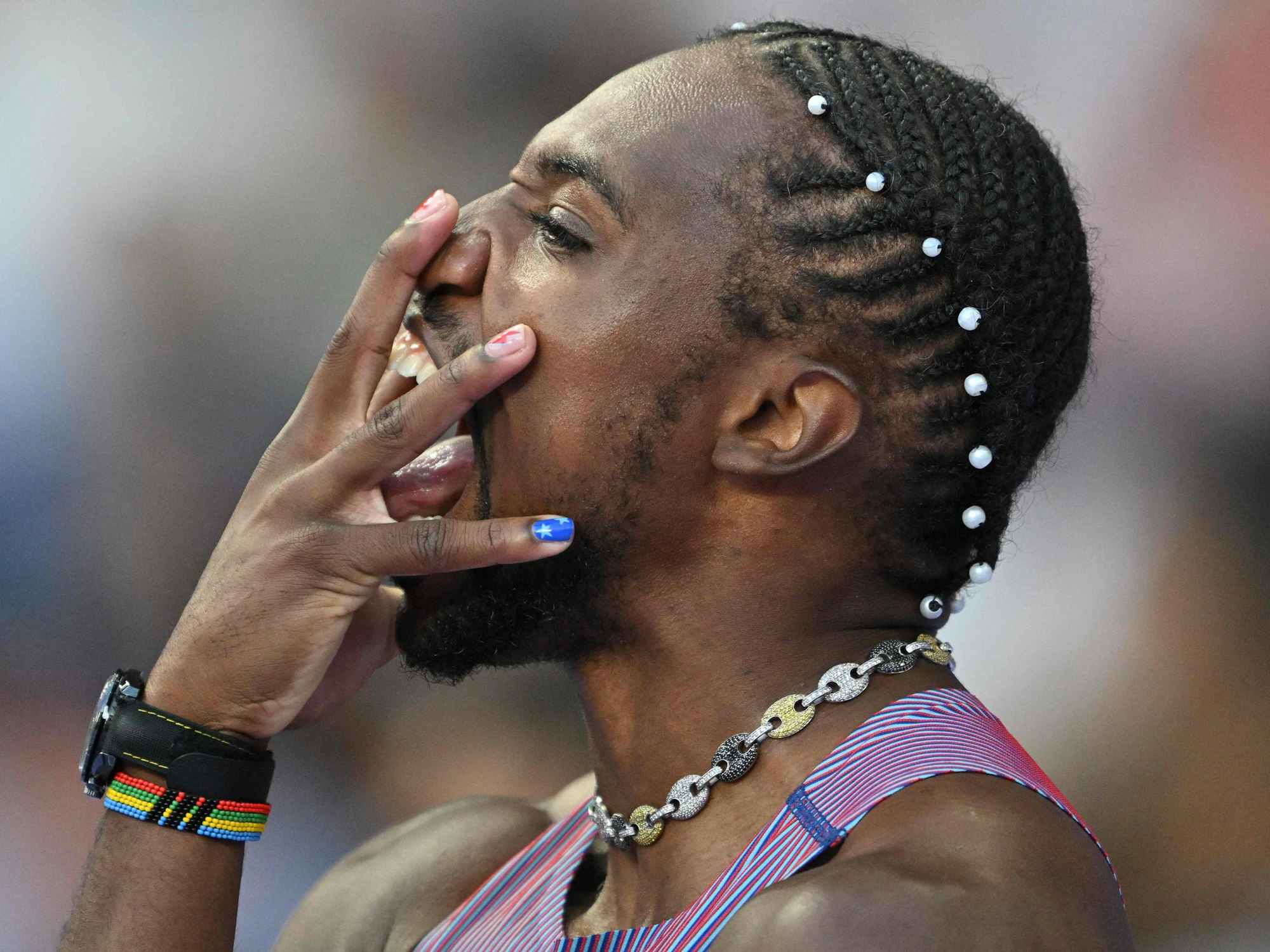 Noah Lyles hält sich vor dem Rennen die Hand vors Gesicht.