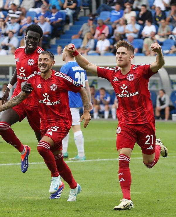 Von l. nach r. Joshua Quarshie, Matthias Zimmermann und Tim Rossmann laufen jubelnd über den Fußballplatz.