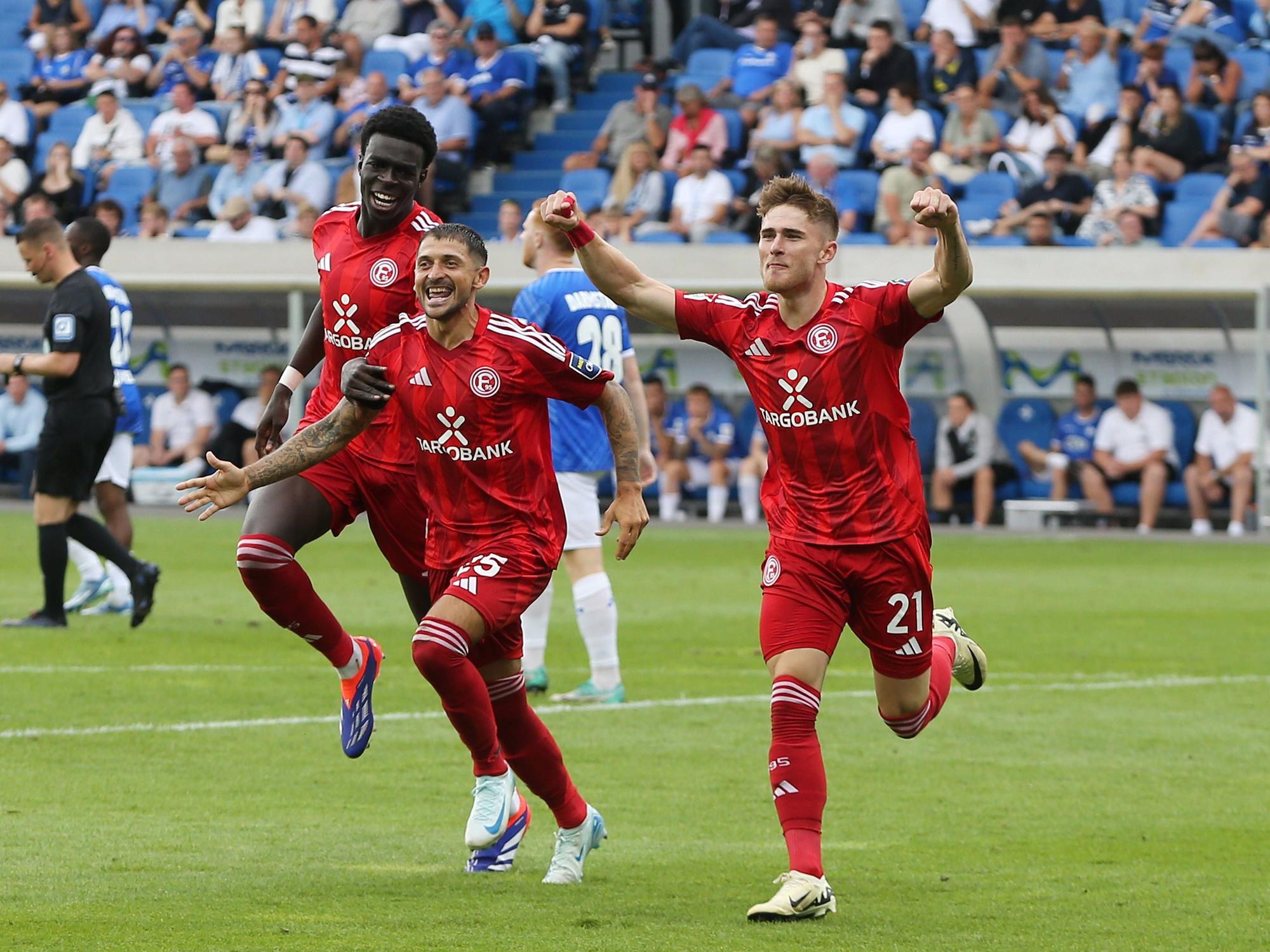Von l. nach r. Joshua Quarshie, Matthias Zimmermann und Tim Rossmann laufen jubelnd über den Fußballplatz.