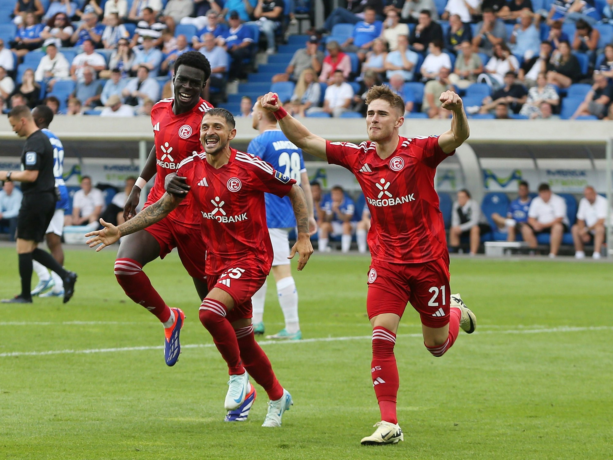 Von l. nach r. Joshua Quarshie, Matthias Zimmermann und Tim Rossmann laufen jubelnd über den Fußballplatz.