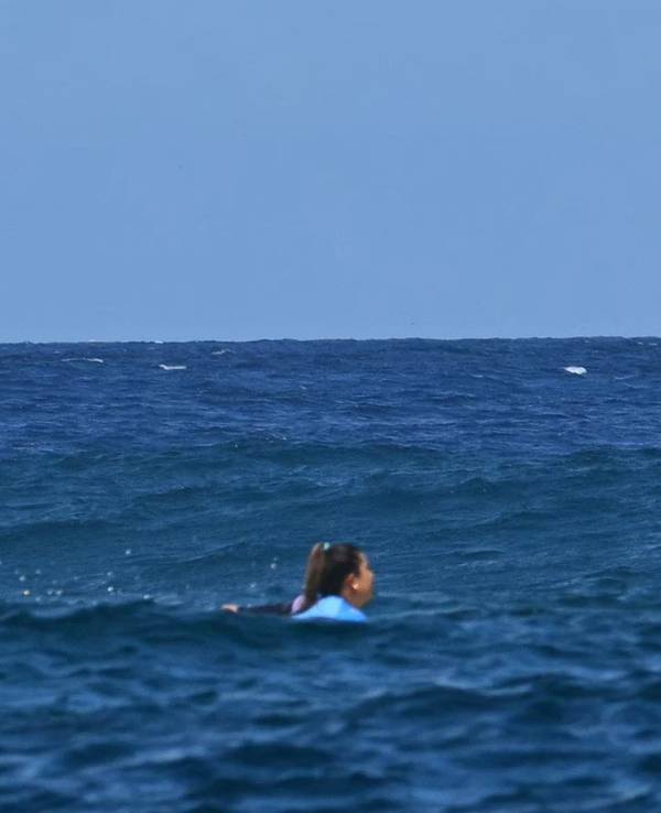 Der riesige Wal springt direkt hinter der Surferin Brisa Hennessy aus dem Wasser.