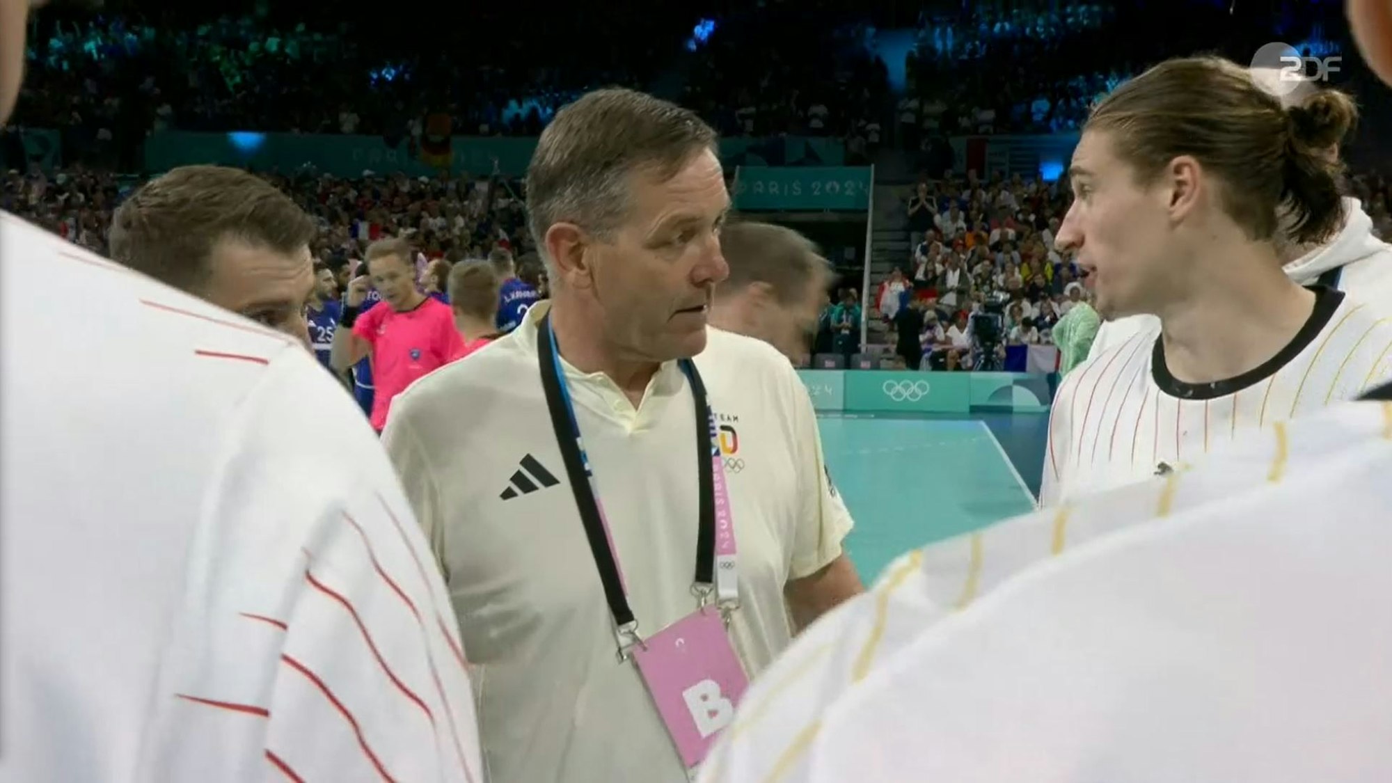 Handball-Bundestrainer Alfred Gislason und Nationalspieler Juri Knorr im Dialog beim Olympia-Viertelfinale gegen Frankreich am 7. August 2024.