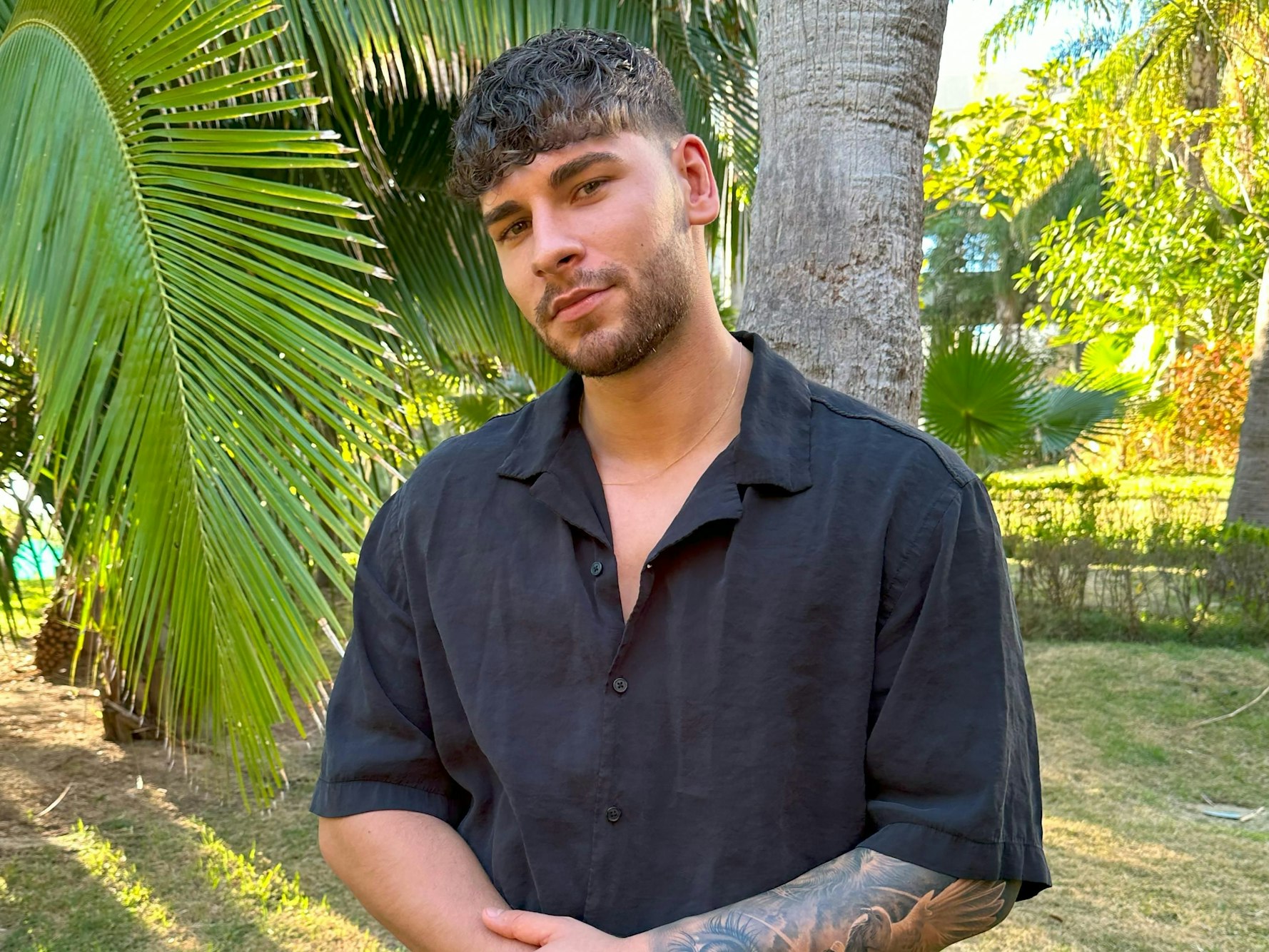 Das Foto zeigt den Ex on the Beach-Kandidaten Fabi Jang vor einer Reihe von Palmen.