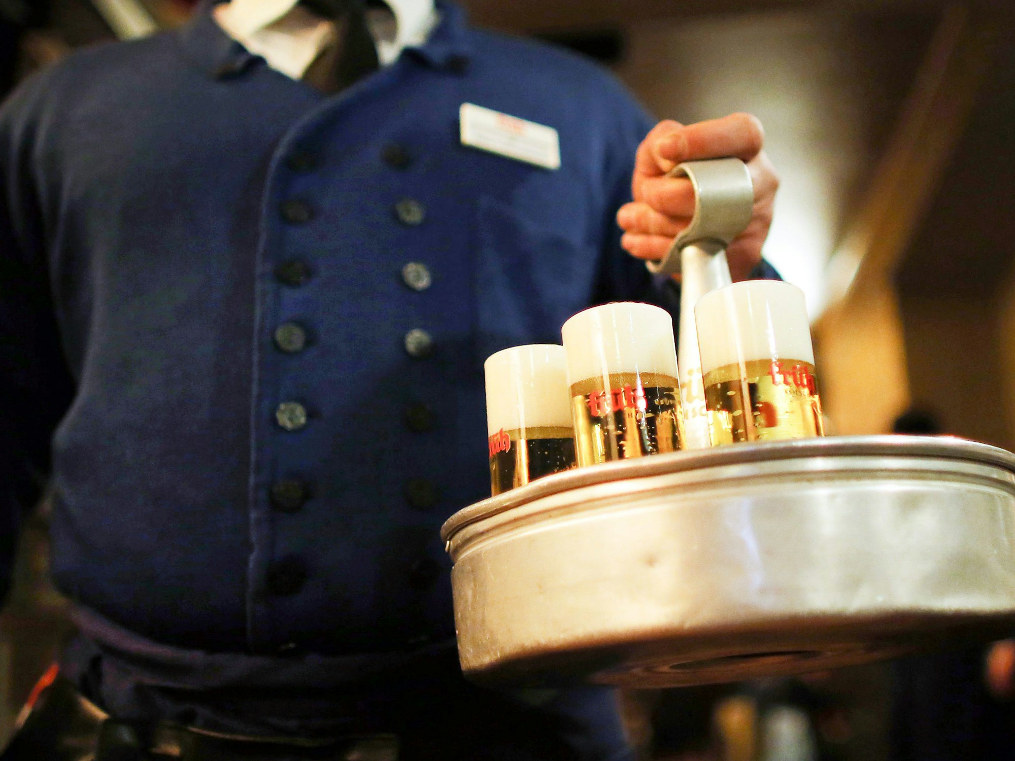 Ein Köbes (Kellner) trägt im Brauhaus Früh am Dom Kölsch-Bier.