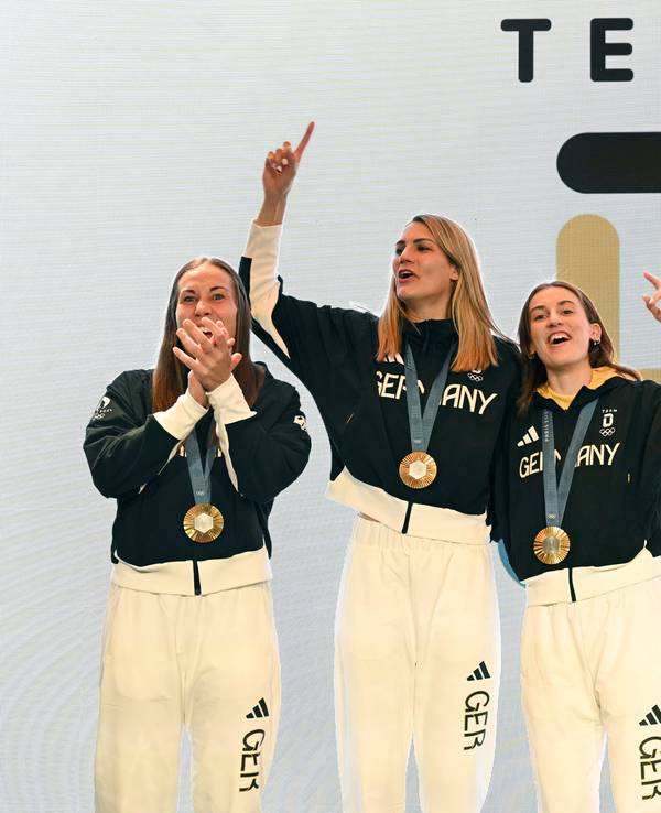 Die deutschen Basketballerinnen Svenja Brunckhorst (l-r), Sonja Greinacher, Elisa Mevius und Marie Reichert feiern am 6. August 2024 mit der Goldmedaille im Deutschen Haus.
