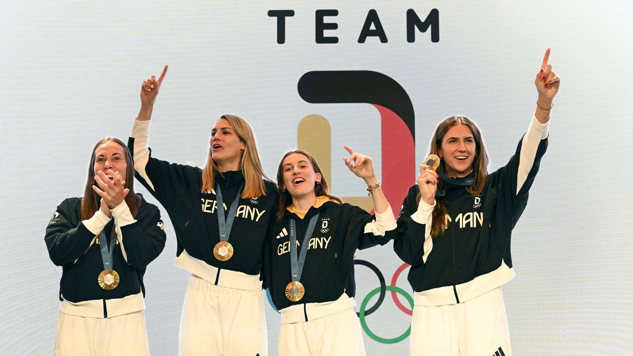 Die deutschen Basketballerinnen Svenja Brunckhorst (l-r), Sonja Greinacher, Elisa Mevius und Marie Reichert feiern am 6. August 2024 mit der Goldmedaille im Deutschen Haus.