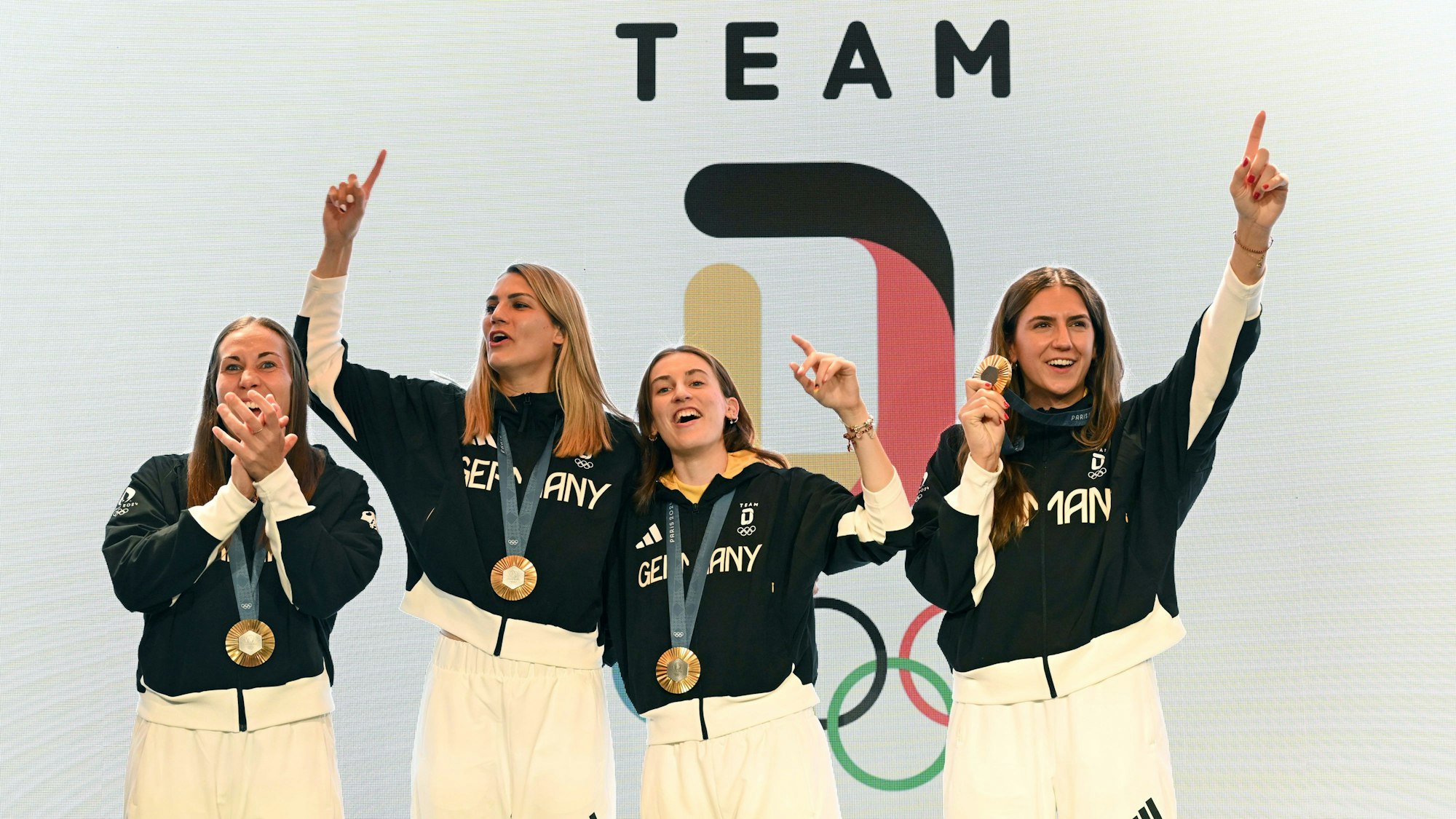 Die deutschen Basketballerinnen Svenja Brunckhorst (l-r), Sonja Greinacher, Elisa Mevius und Marie Reichert feiern am 6. August 2024 mit der Goldmedaille im Deutschen Haus.