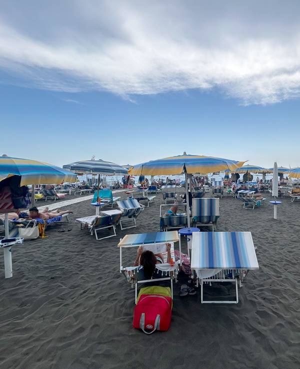 Menschen liegen auf Strandliegen unter Sonnenschirmen am Mittelmeer in Ostia in der Nähe von Rom. Am Freitag (9. August 2024) findet ein großer „Sonnenschirm-Protest“ statt.