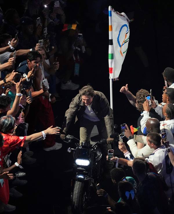 Tom Cruise rast bei der Olympia-Abschlussfeier mit der olympischen Flagge auf einem Motorrad aus dem Stade de France.