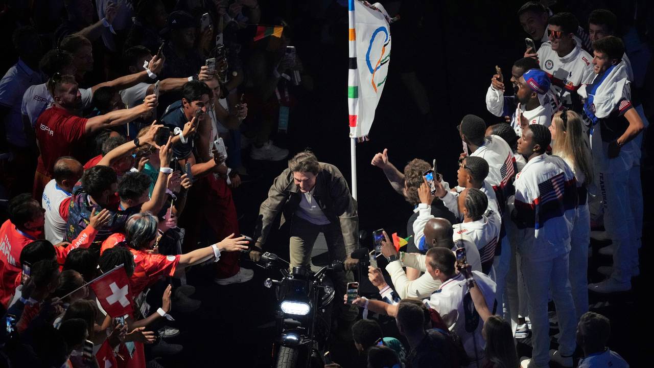 Tom Cruise rast bei der Olympia-Abschlussfeier mit der olympischen Flagge auf einem Motorrad aus dem Stade de France.