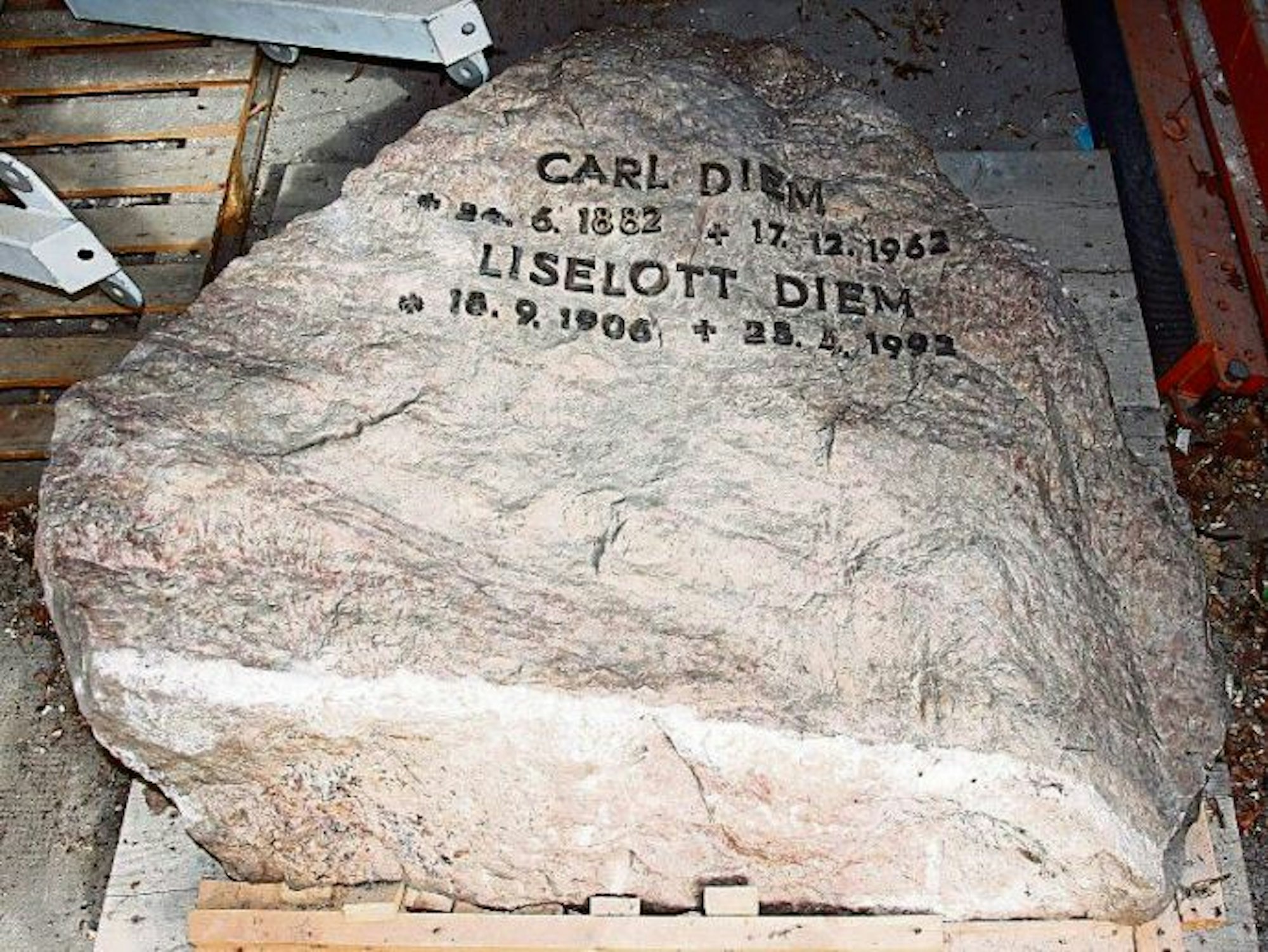 Ein Grabstein mit Namen und Lebensdaten von Carl Diem und seiner Frau Liselott liegt auf dem Boden.