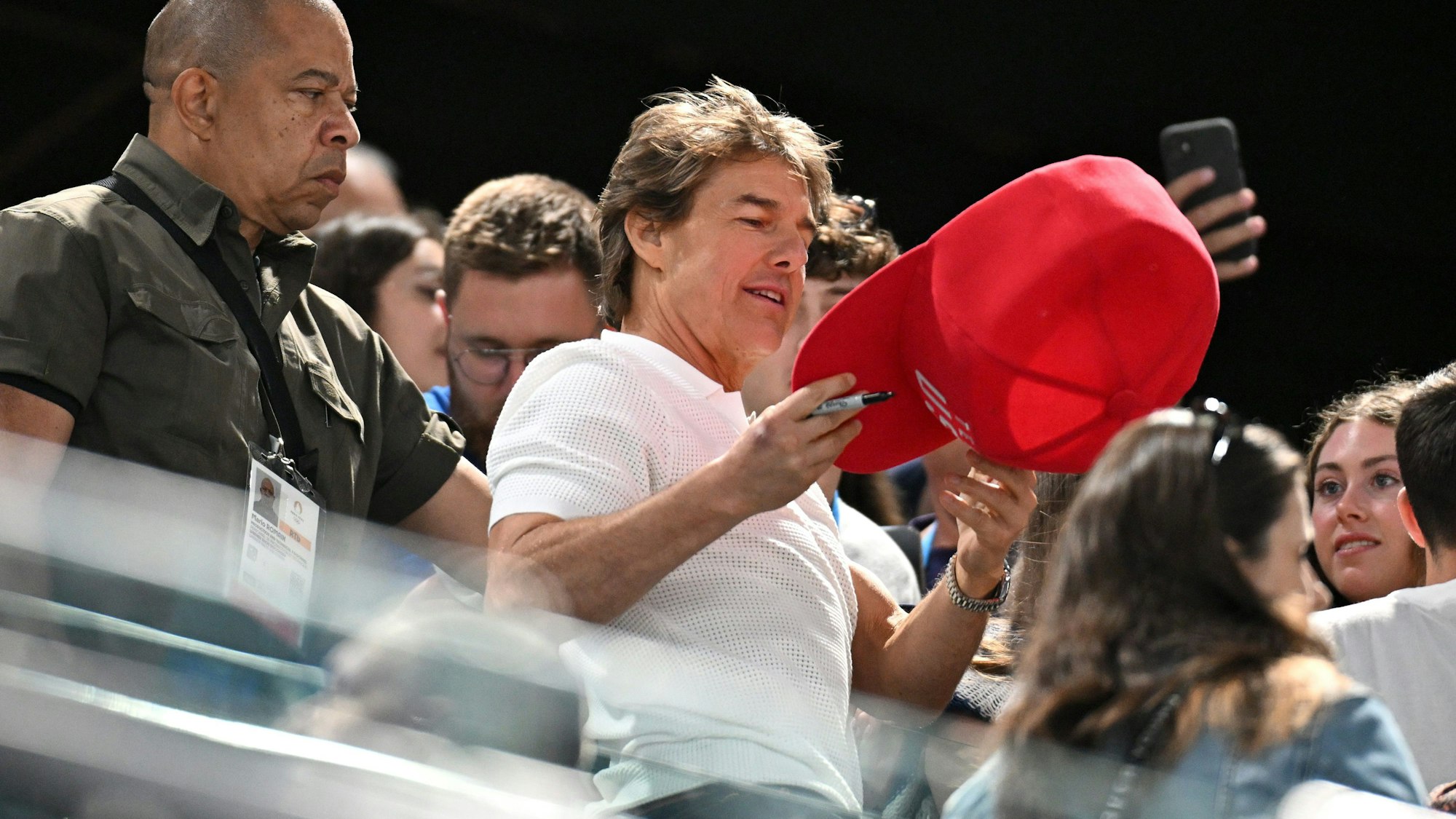 Tom Cruise schreibt bei Olympia Autogramme.