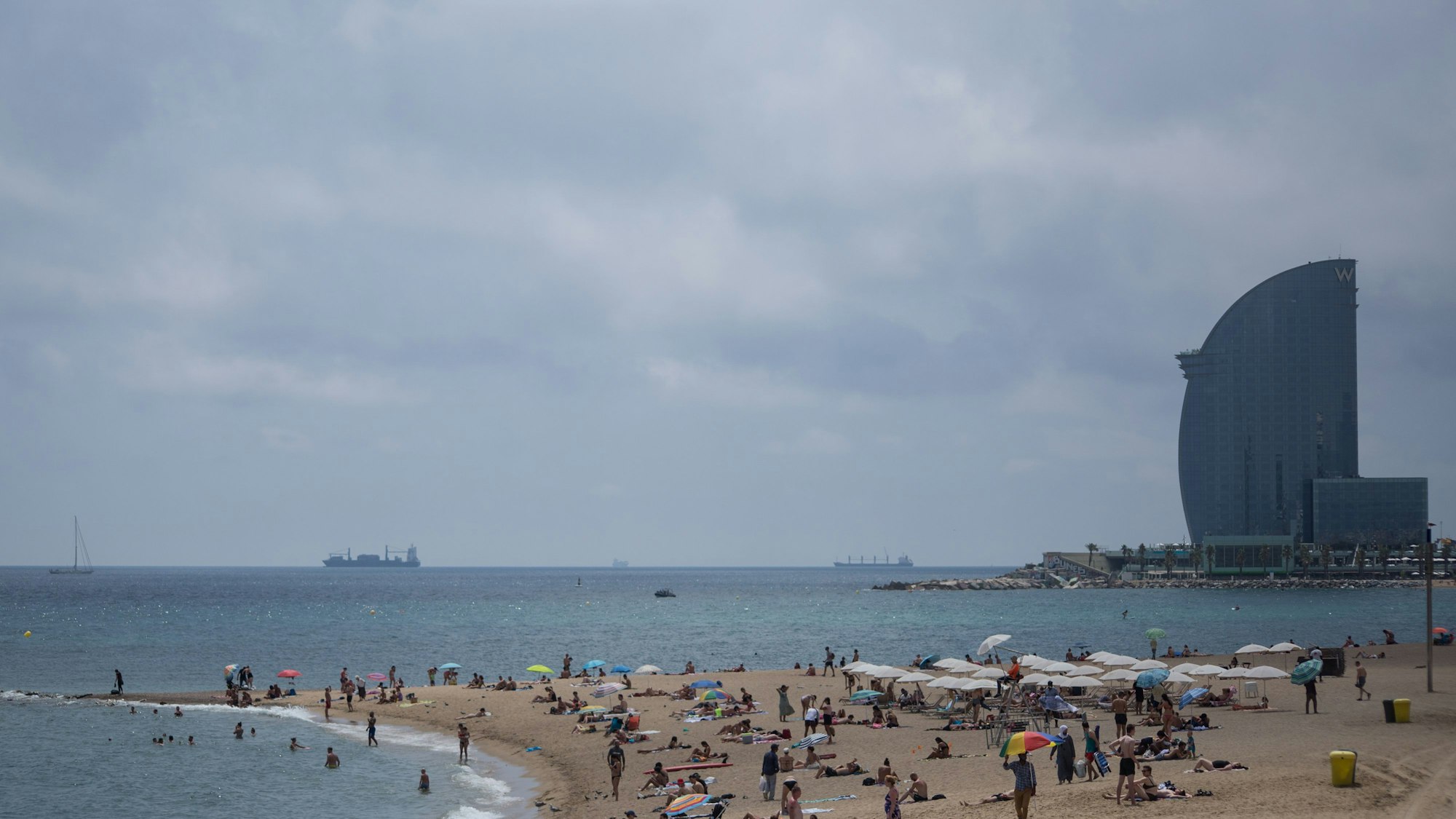 Badegäste stehen am Strand Barceloneta in Barcelona.