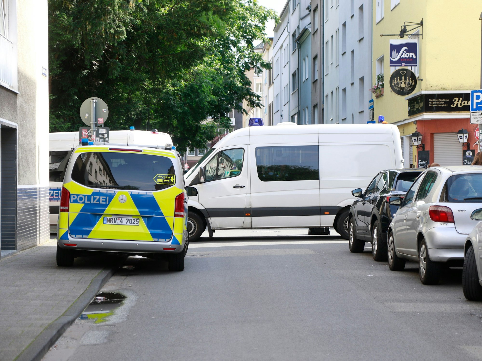 Streifenwagen der Polizei steht an einer engen Straße in Köln.