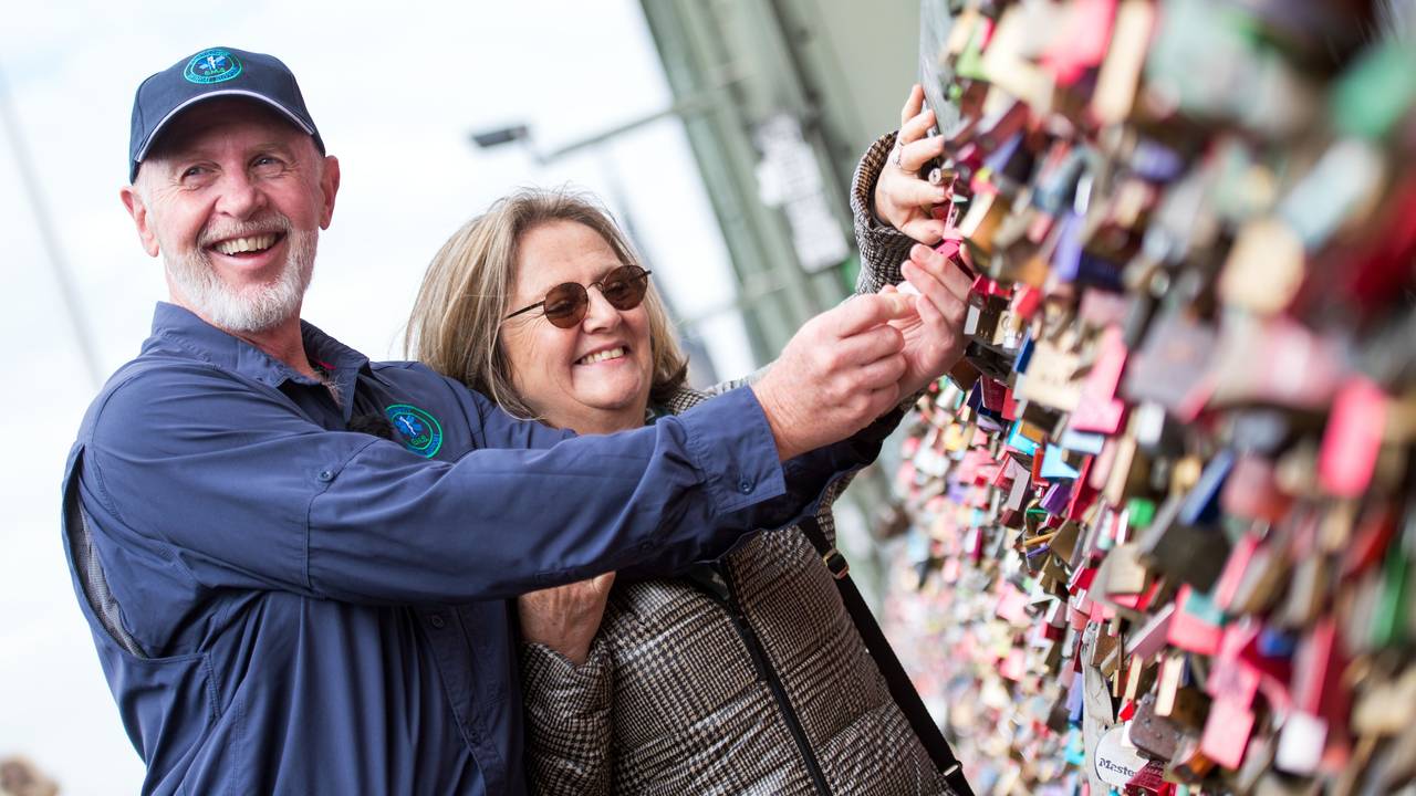 Der australische Special Effect Artist Robert „Bob“ McCarron alias Dr. Bob, bekannt aus der RTL-Show „Ich bin ein Star - Holt mich hier raus!“, und Ehefrau Annette Miles bringen am 30.07.2015 an der Hohenzollernbrücke in Köln (Nordrhein-Westfalen) ein Liebesschloss an.