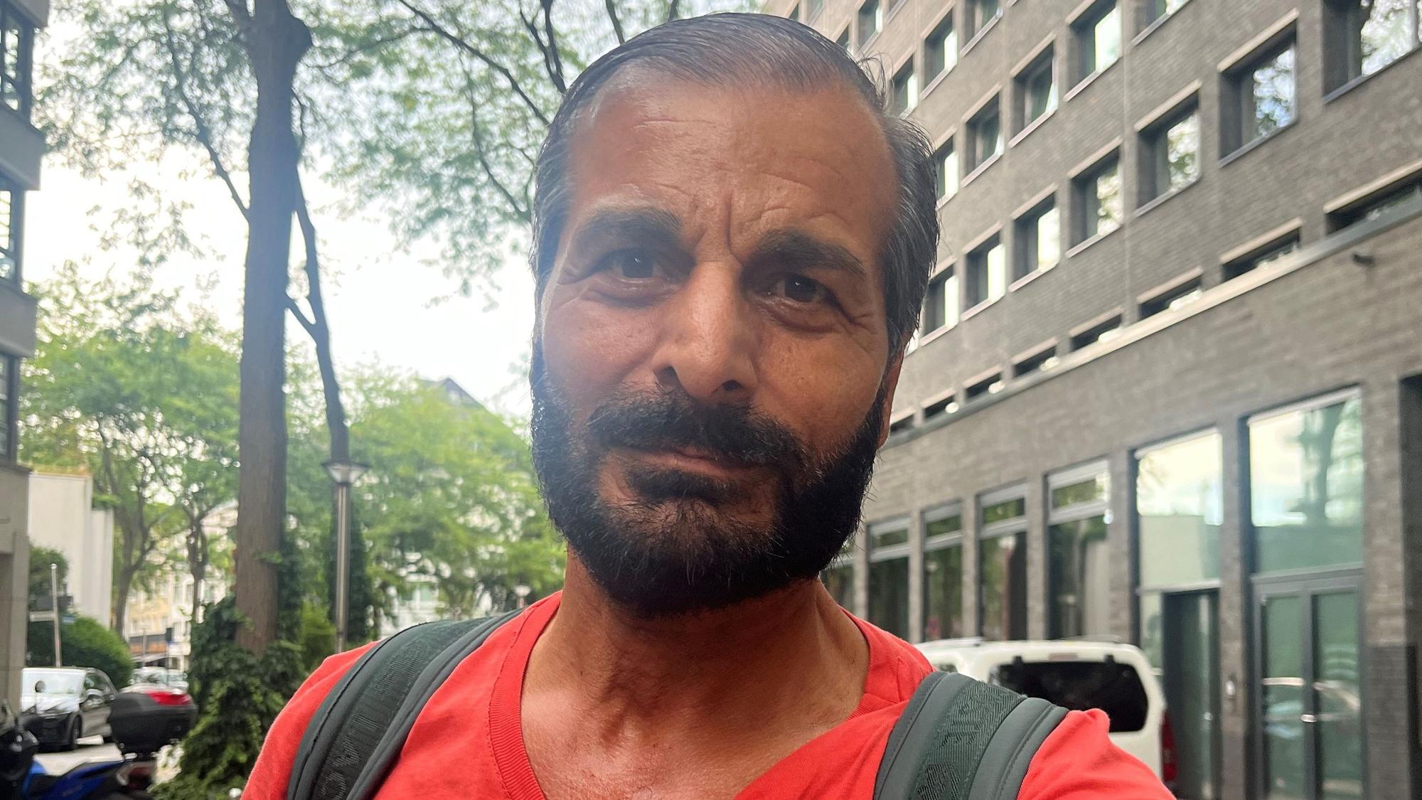 Ein Mann mit Vollbart steht in einer Straße.
