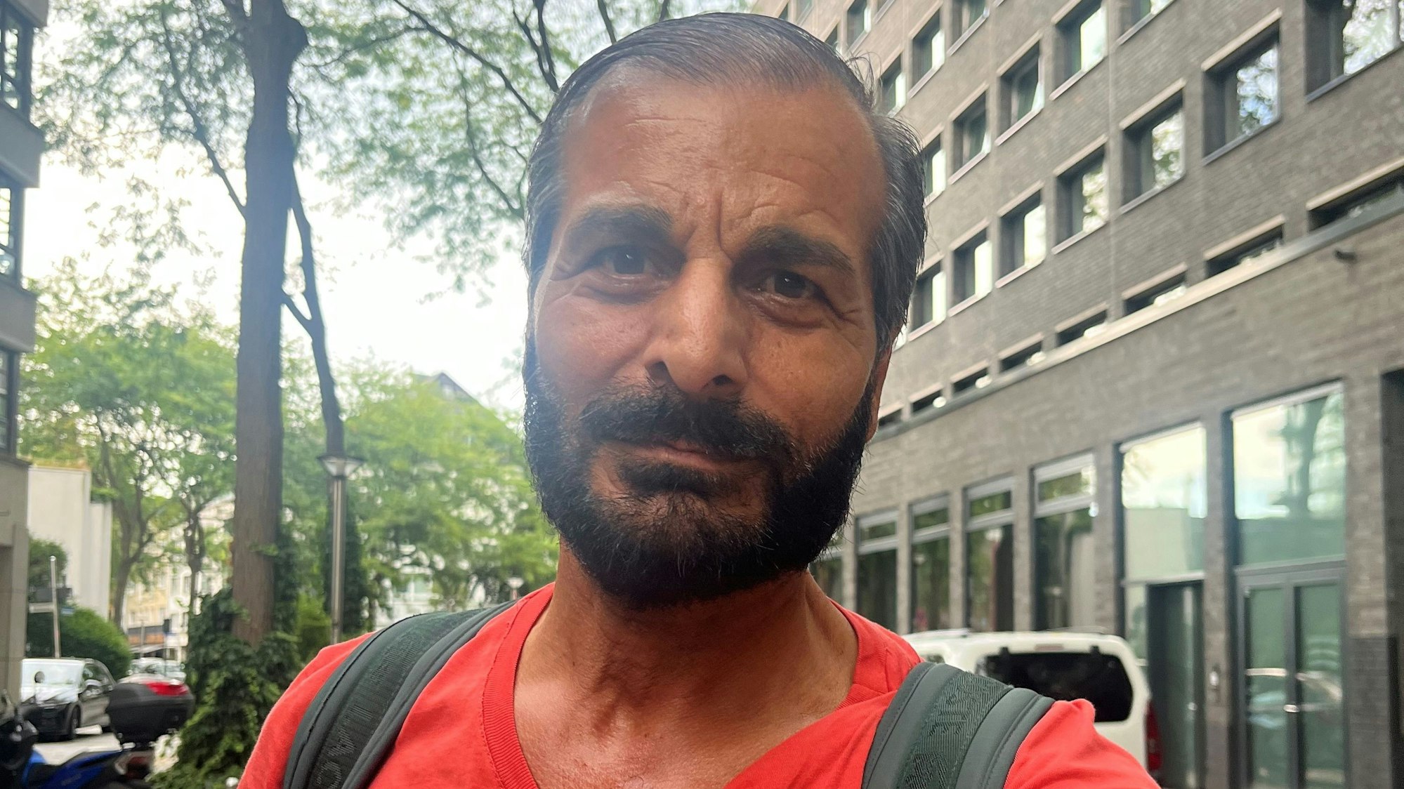 Ein Mann mit Vollbart steht in einer Straße.