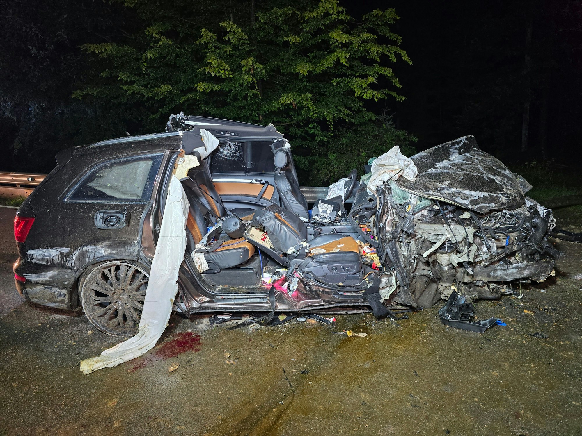 Ein völlig zerstörtes Auto steht nach einem Unfall auf der Straße.