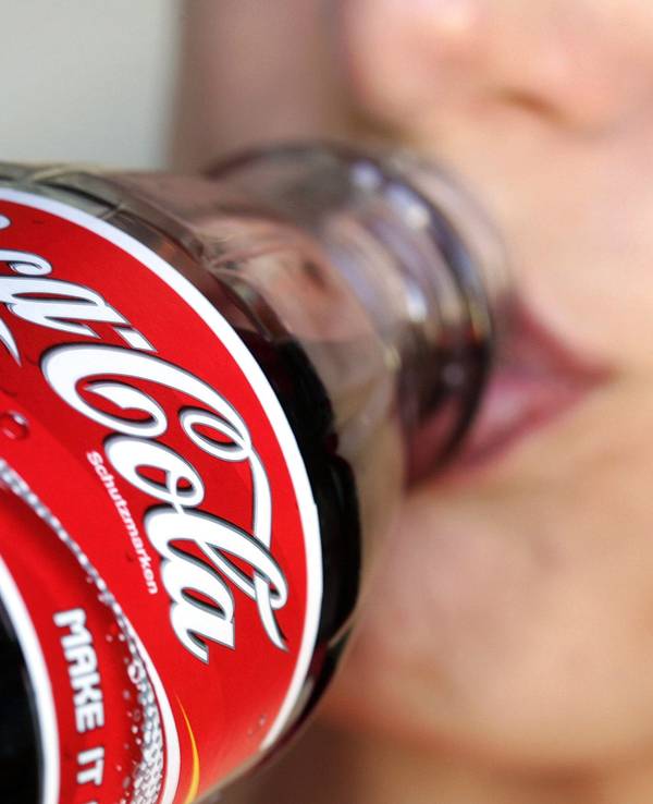 Eine Frau trinkt aus einer Flasche Coca-Cola.
