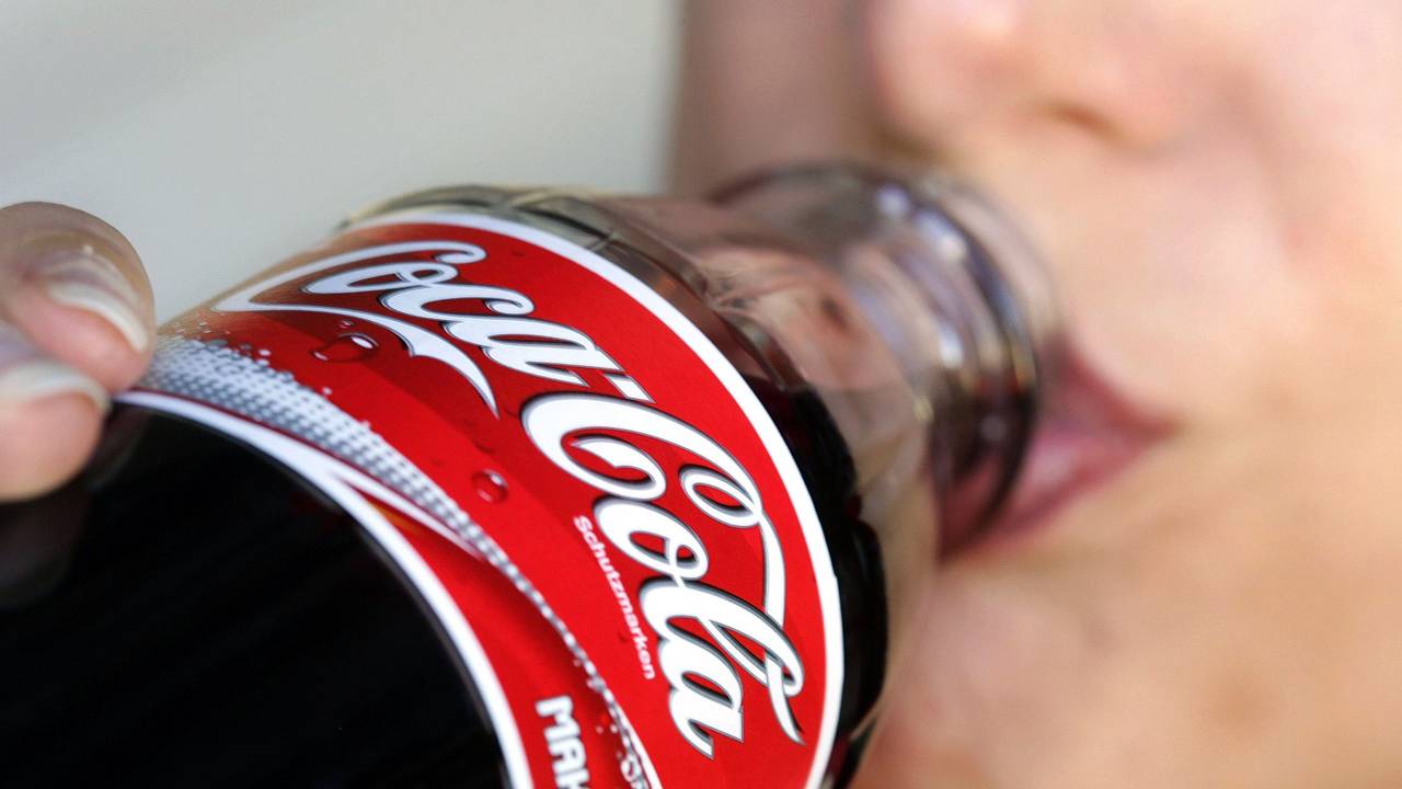 Eine Frau trinkt aus einer Flasche Coca-Cola.