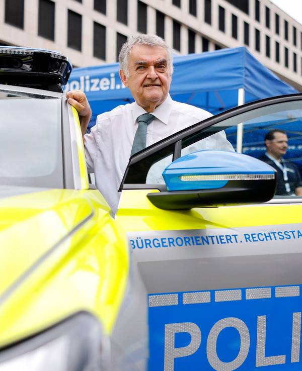 NRW-Innenminister Herbert Reul in der Fahrertür eines E-Polizei-Autos.