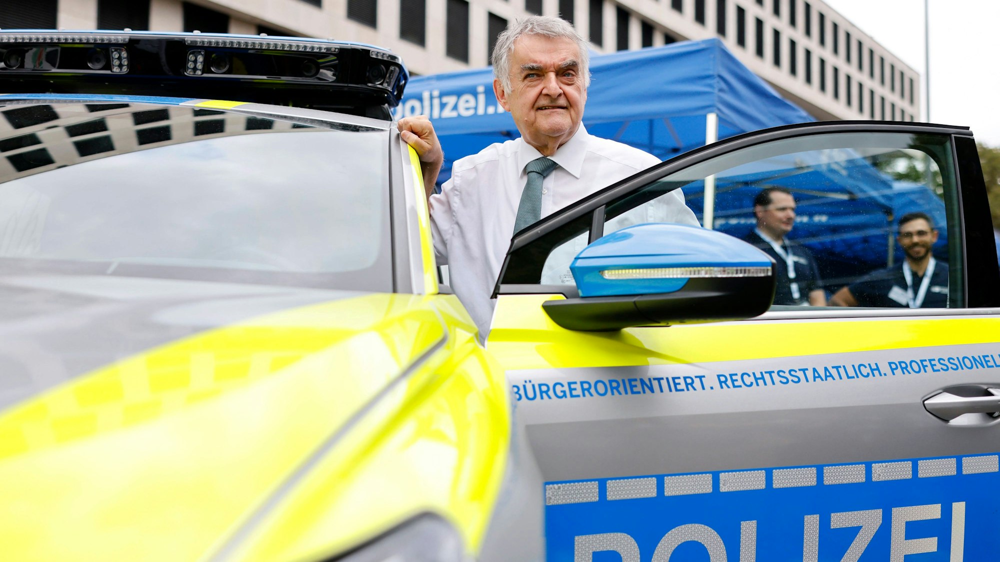 NRW-Innenminister Herbert Reul in der Fahrertür eines E-Polizei-Autos.