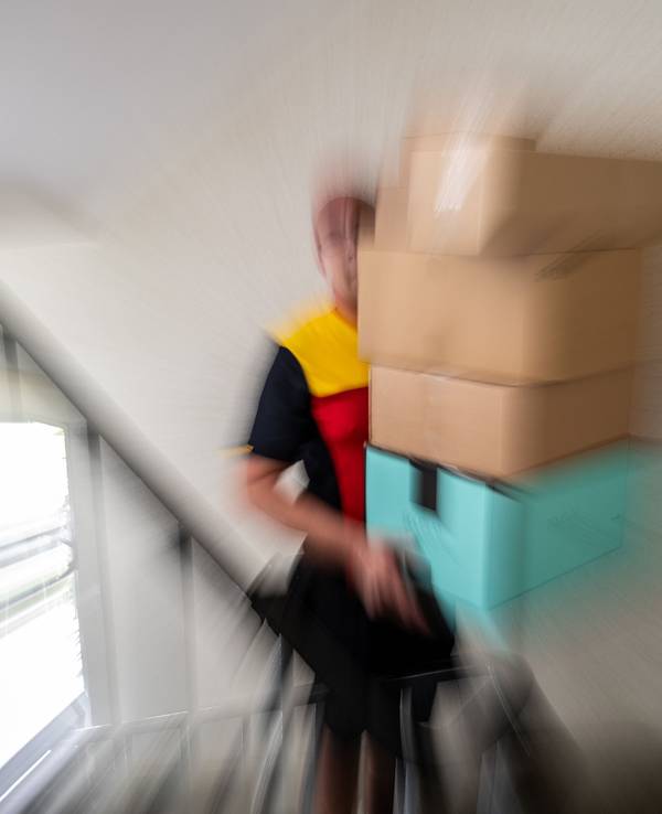 Ein Postbote trägt mehrere Pakete.