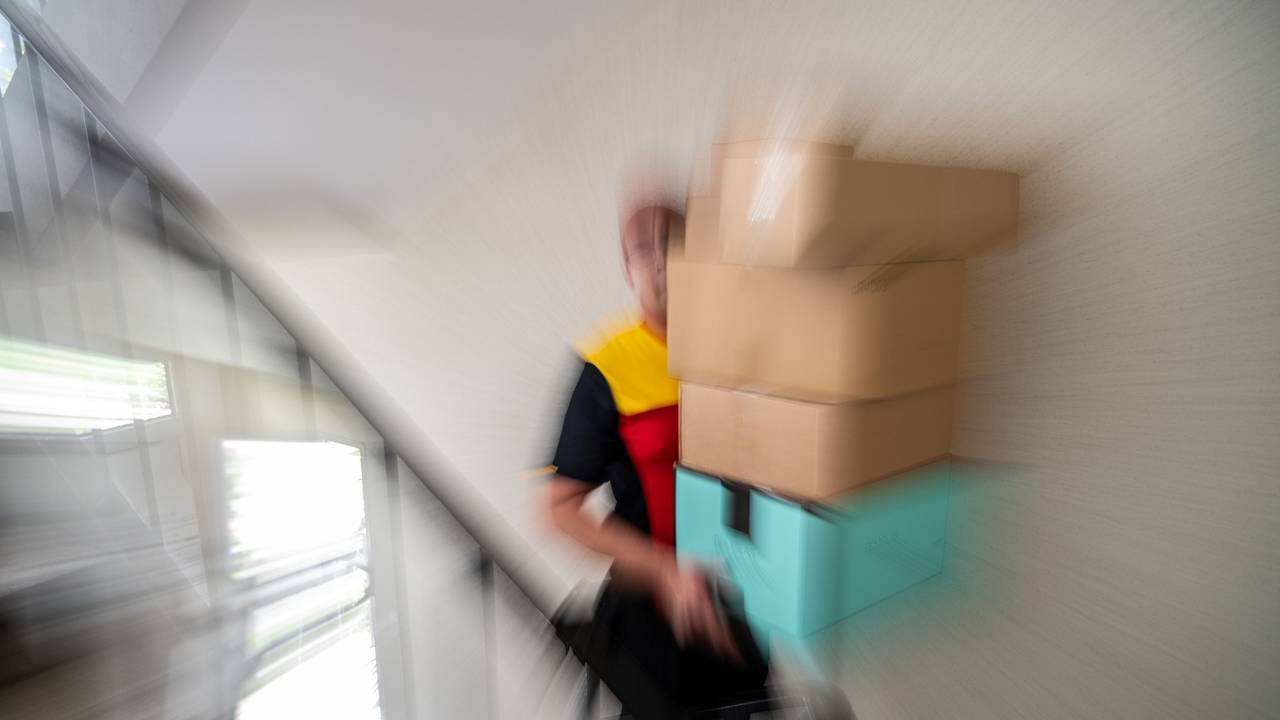 Ein Postbote trägt mehrere Pakete.