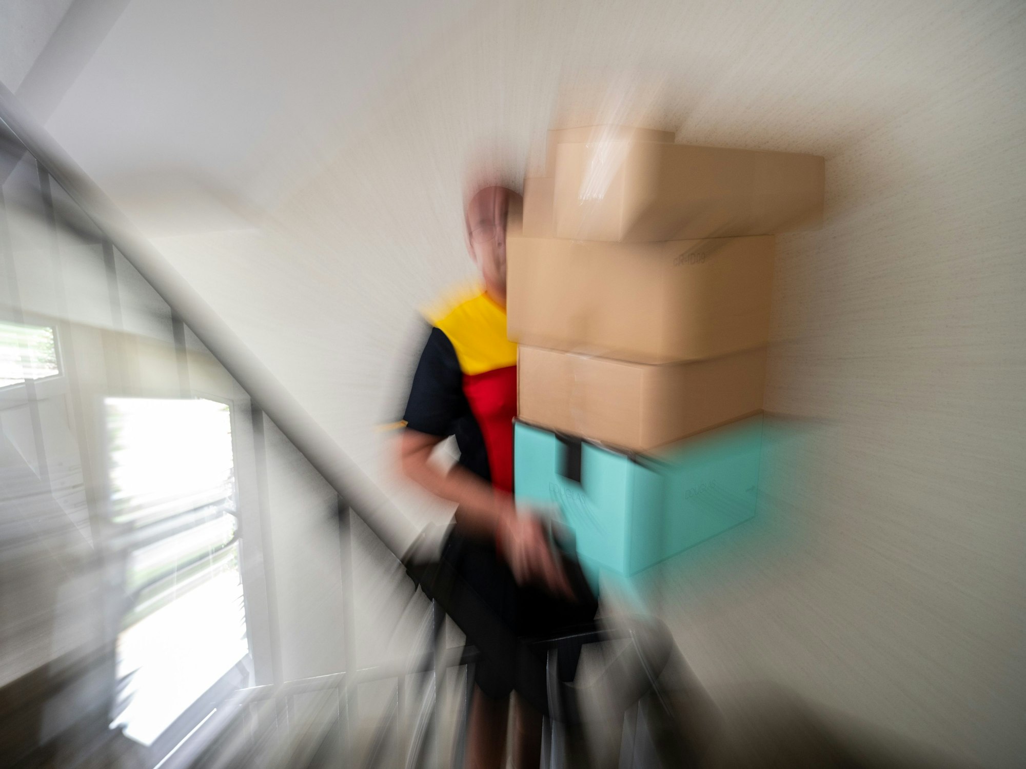 Ein Paketzusteller trägt Päckchen die Treppen hoch.