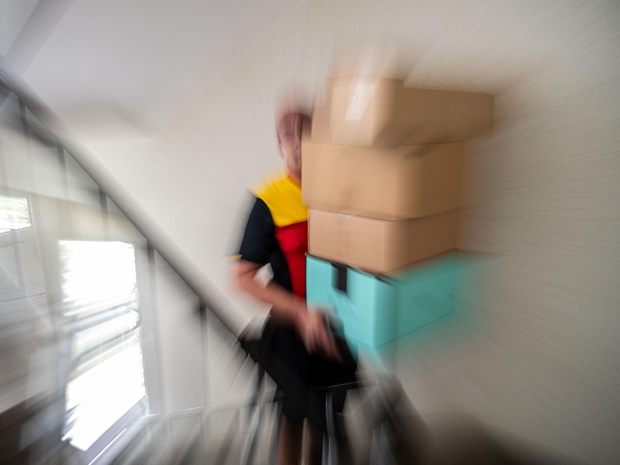 Ein Postbote trägt mehrere Pakete.