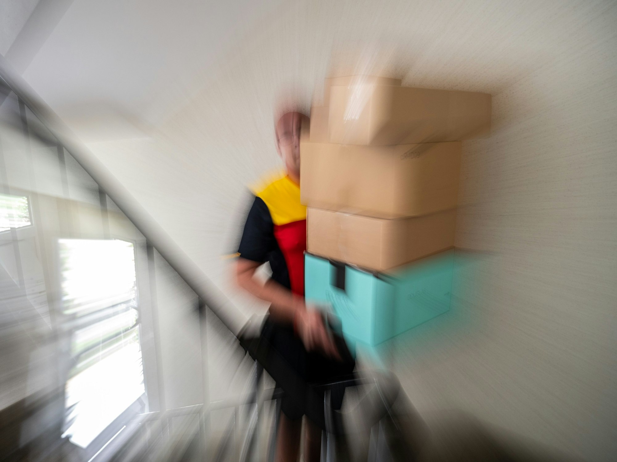 Ein Postbote trägt mehrere Pakete.