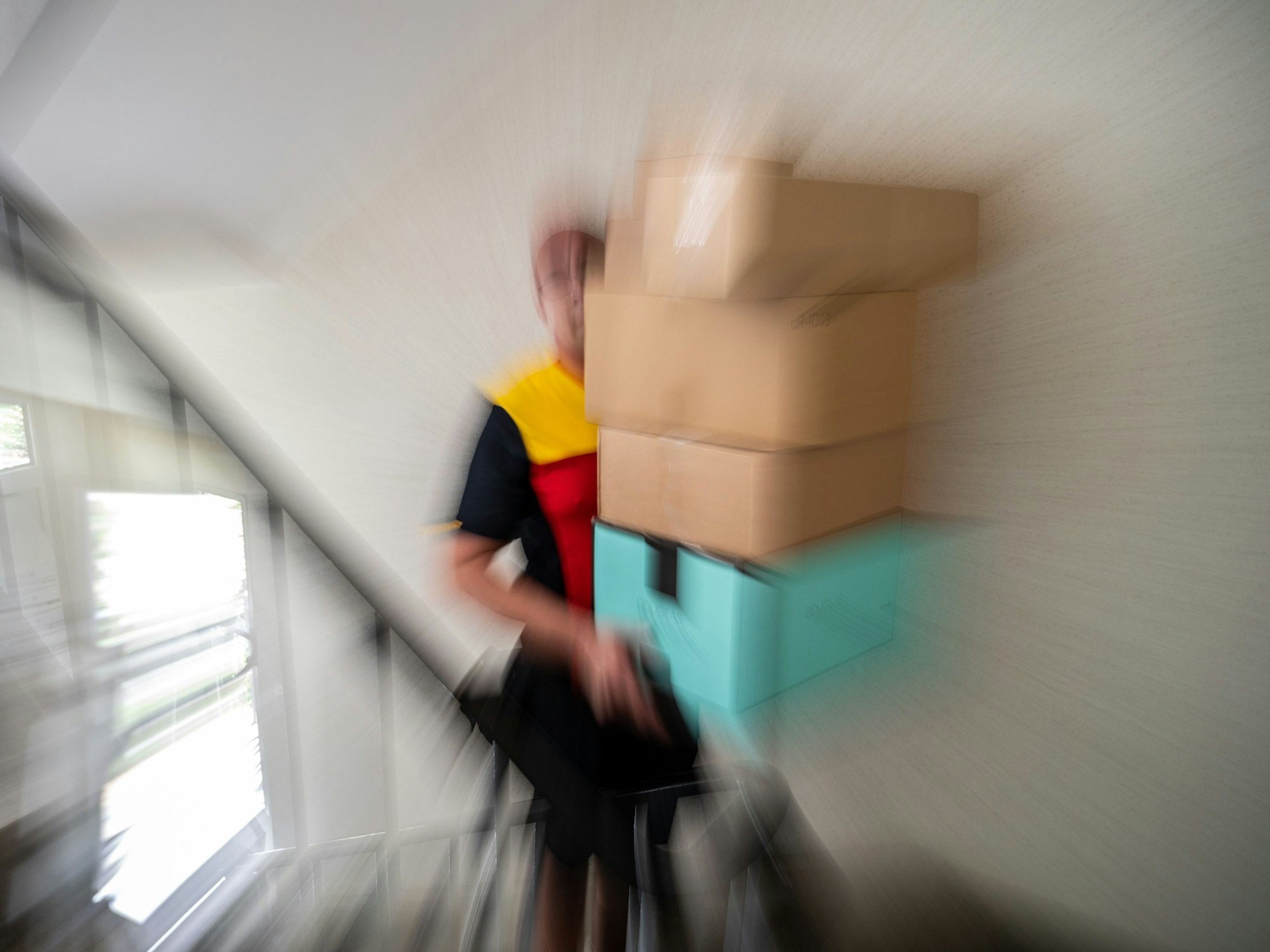 Ein Paketbote trägt Pakete die Treppen hoch.
