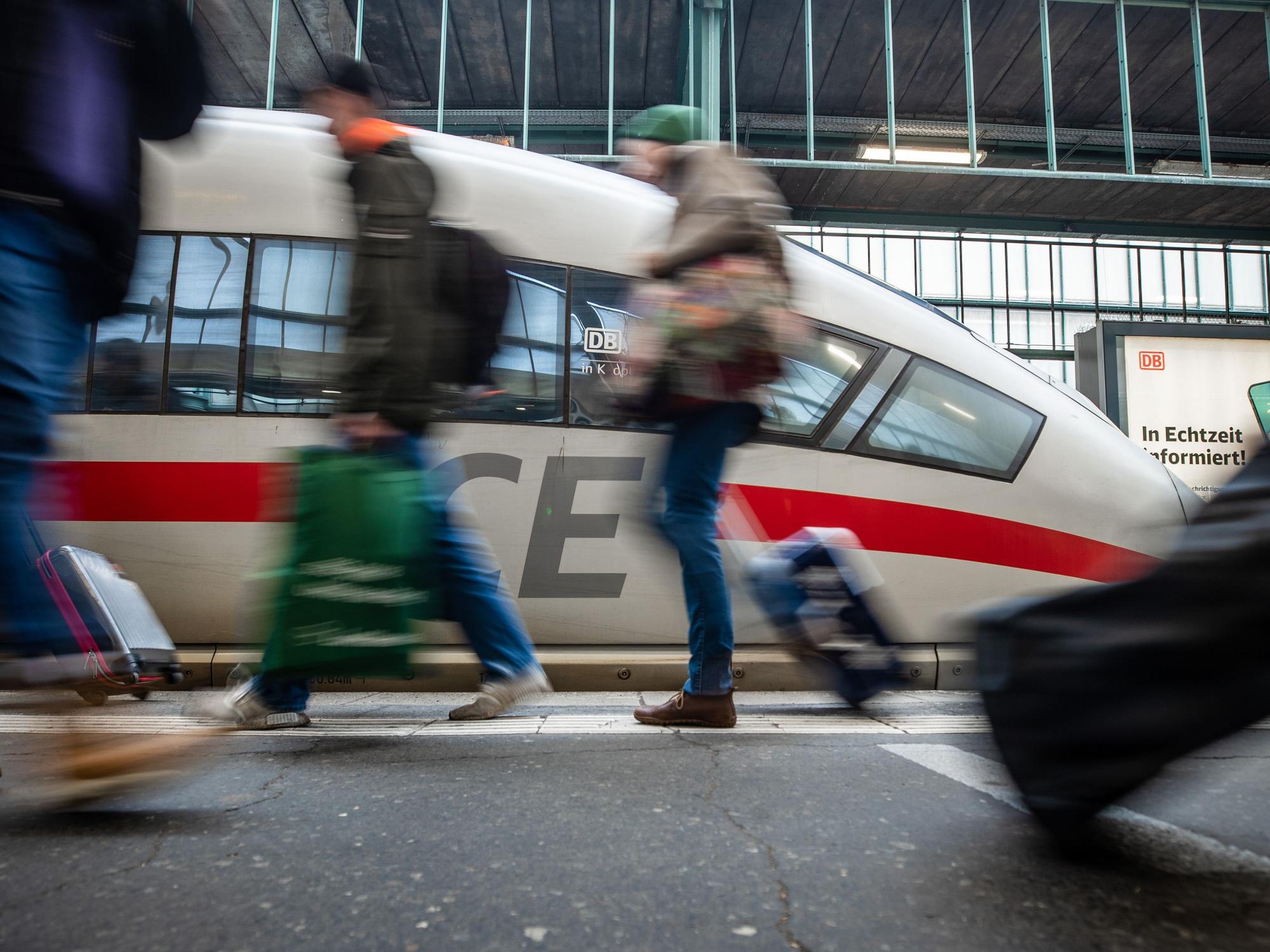 Fahrgäste laufen an einem Bahnsteig des Stuttgarter Hauptbahnhofs an einem ICE vorbei.