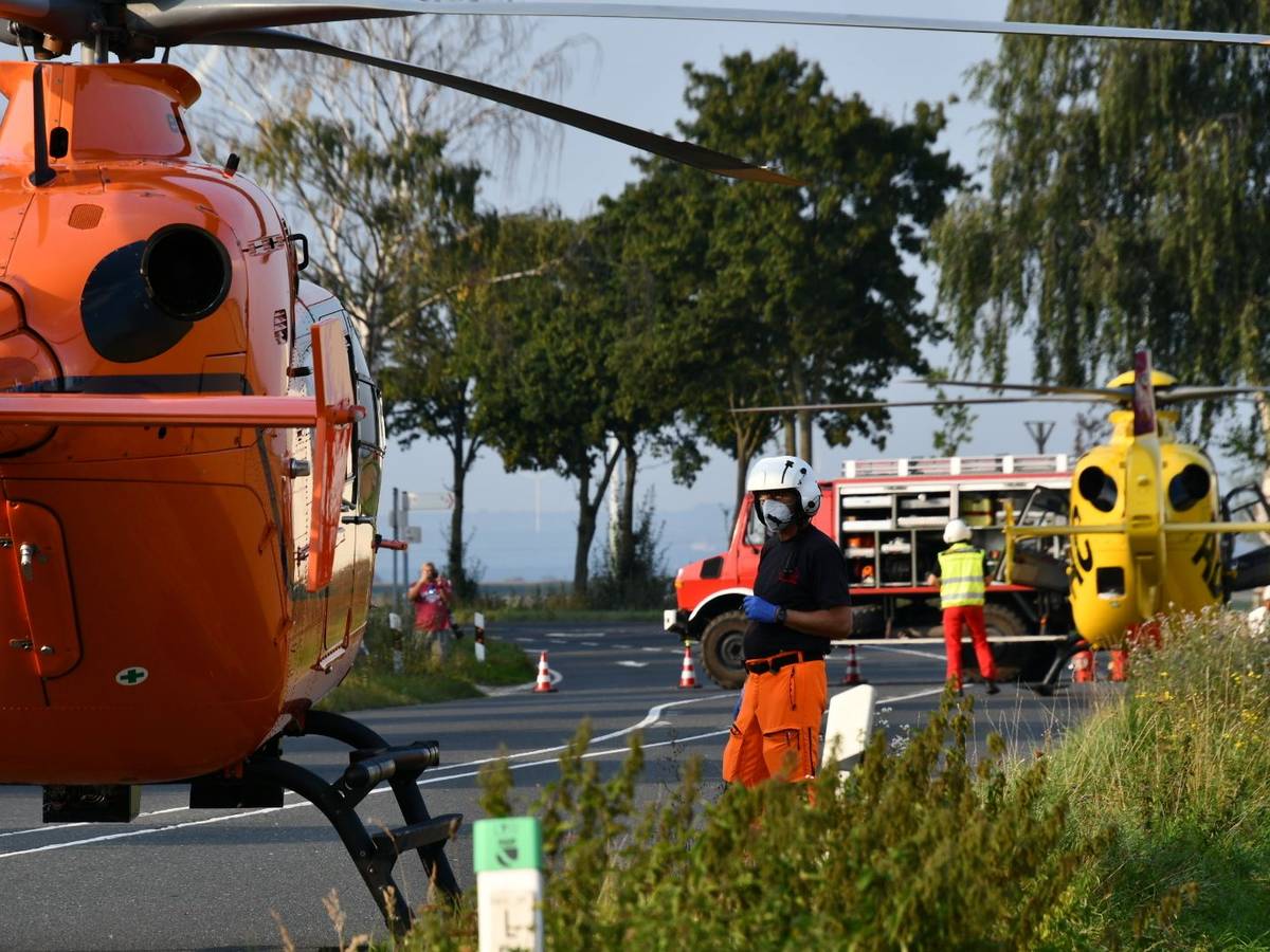 Einsatzkräfte stehen neben einem Rettungshubschrauber auf einer Landstraße (Symbolfoto).
