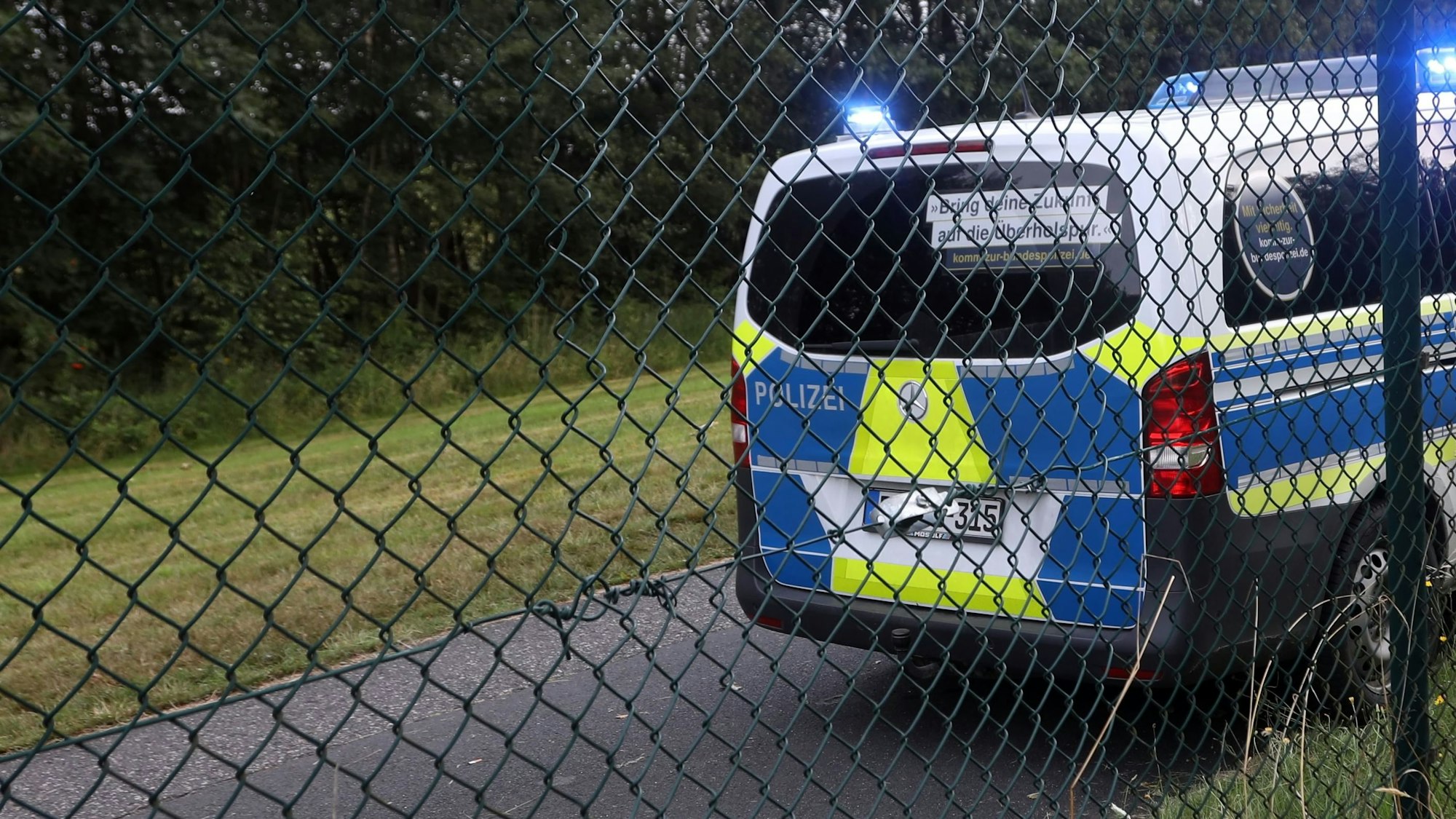 Ein Polizeifahrzeug hinter einem Zaun