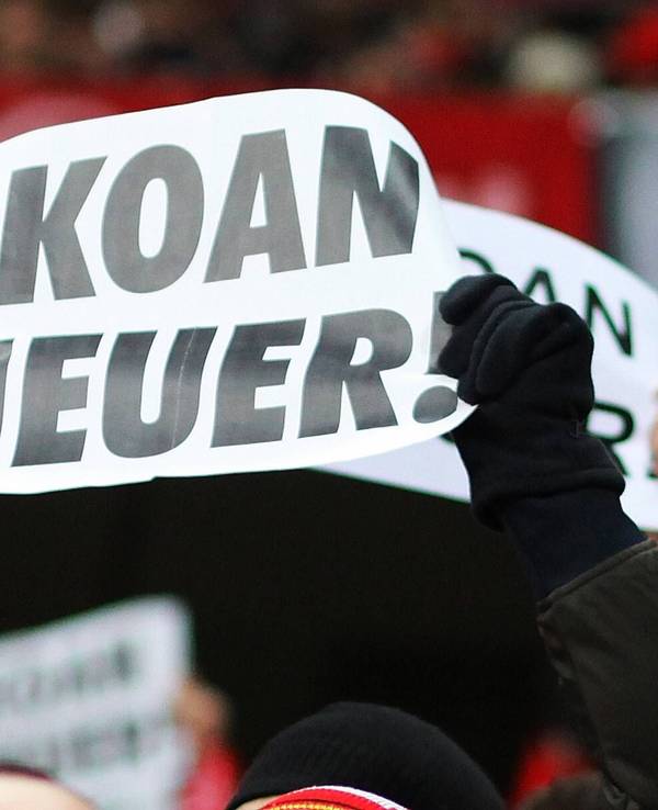 Bayern-Fans halten als Protest gegen den Transferr von Manuel Neuer Plakate mit der Aufschrift „Koan Neuer“ hoch.