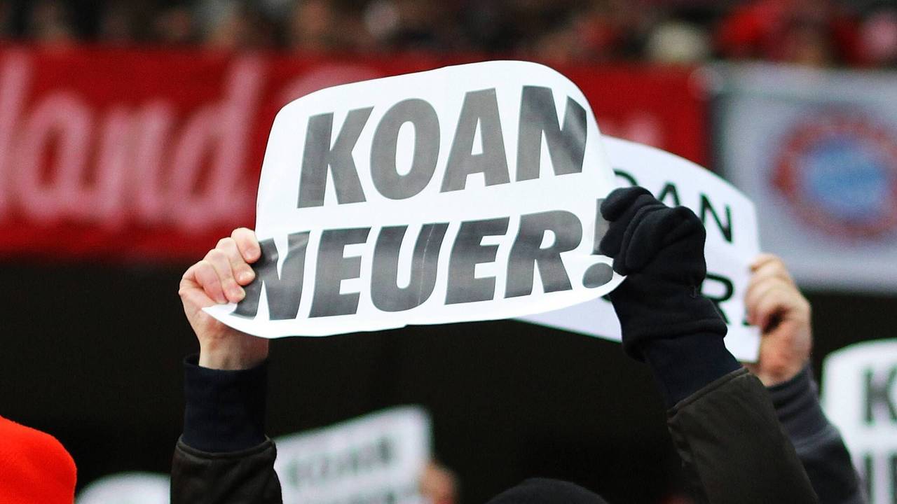 Bayern-Fans halten als Protest gegen den Transferr von Manuel Neuer Plakate mit der Aufschrift „Koan Neuer“ hoch.