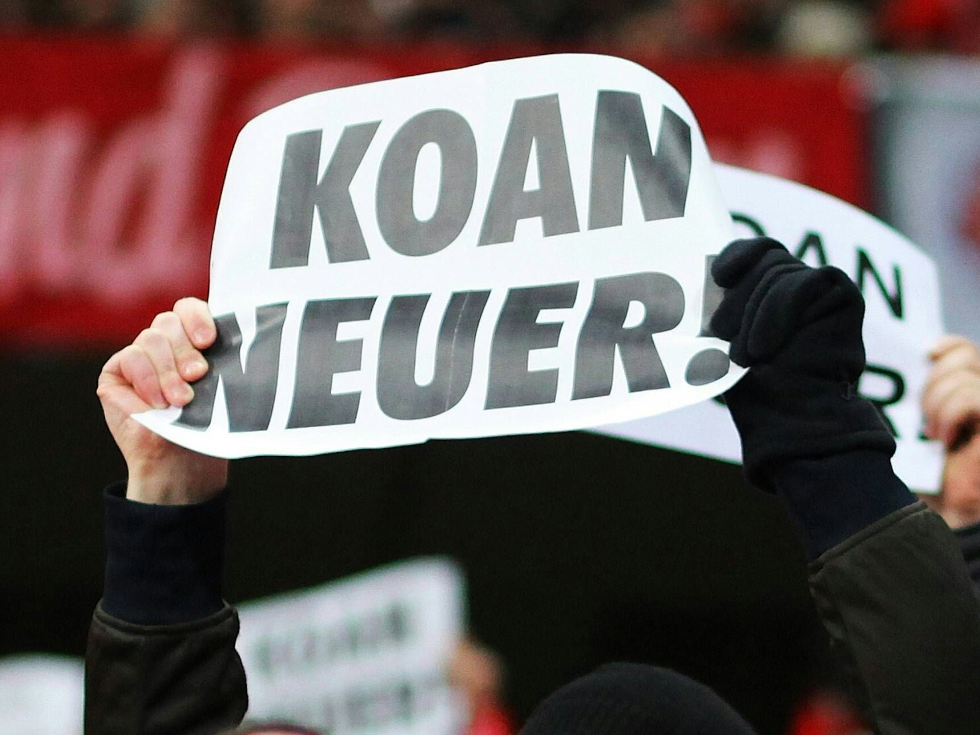 Bayern-Fans halten als Protest gegen den Transferr von Manuel Neuer Plakate mit der Aufschrift „Koan Neuer“ hoch.