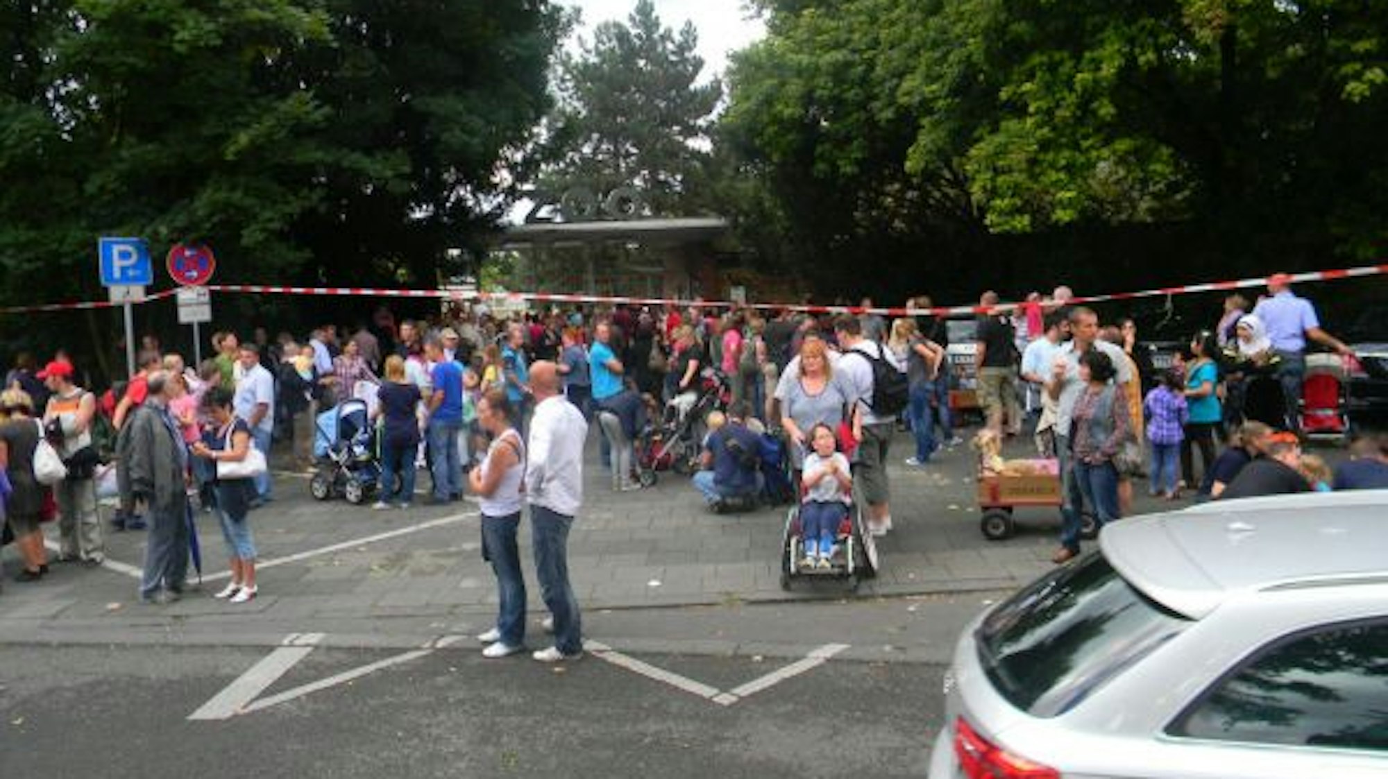 Dutzende Menschen stehen vor dem Kölner Zoo, der evakuiert werden musste.