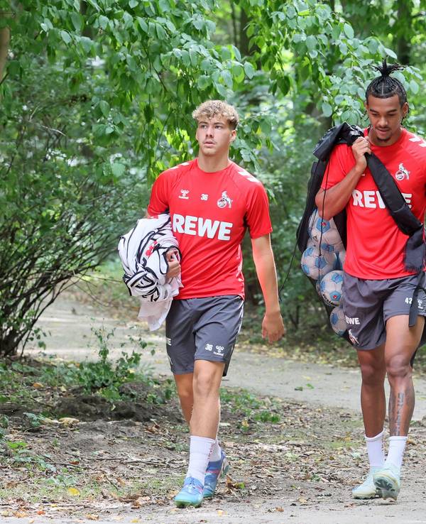 Meiko Wäschenbach und Damion Downs tragen Leibchen und Bälle zum Training. Neben ihnen geht Max Weuthen.