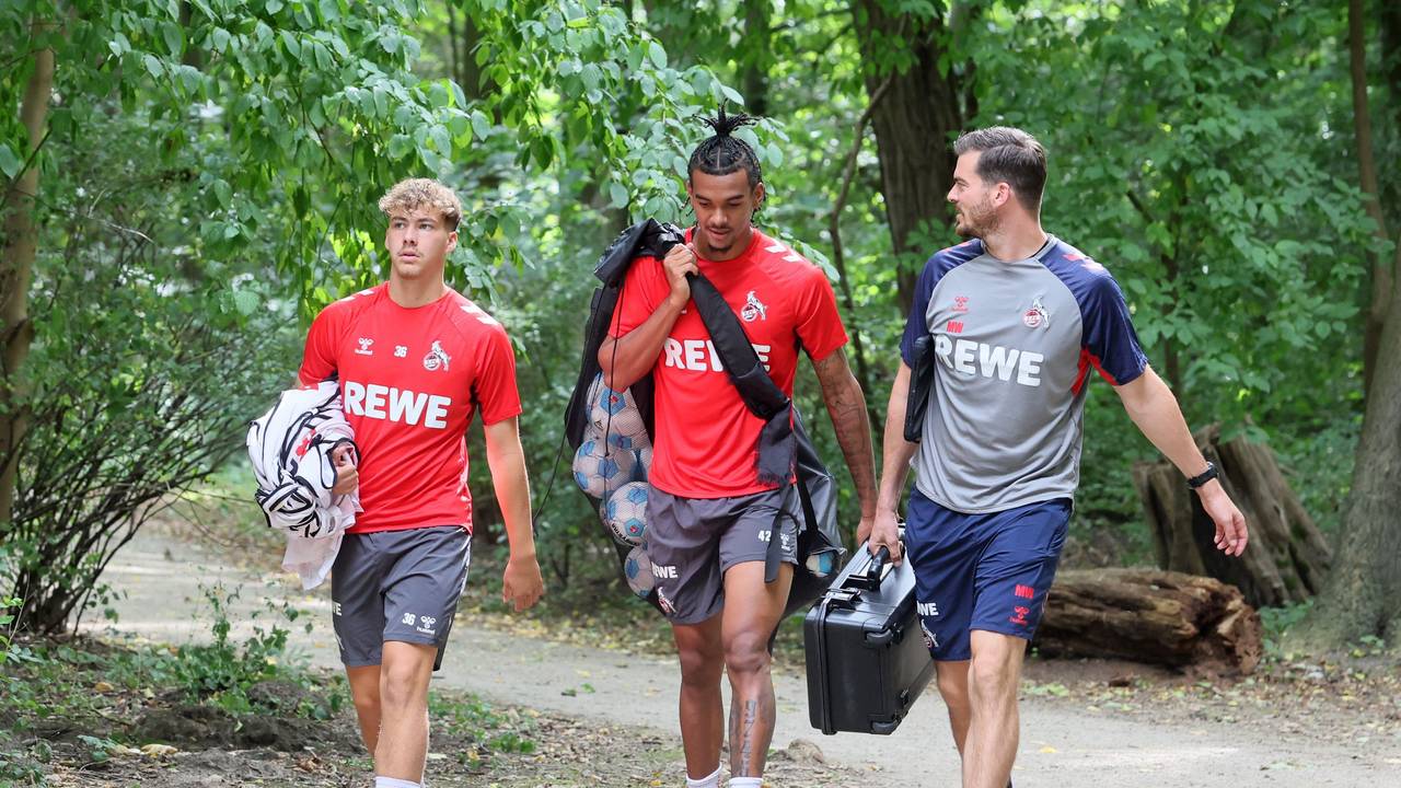 Meiko Wäschenbach und Damion Downs tragen Leibchen und Bälle zum Training. Neben ihnen geht Max Weuthen.