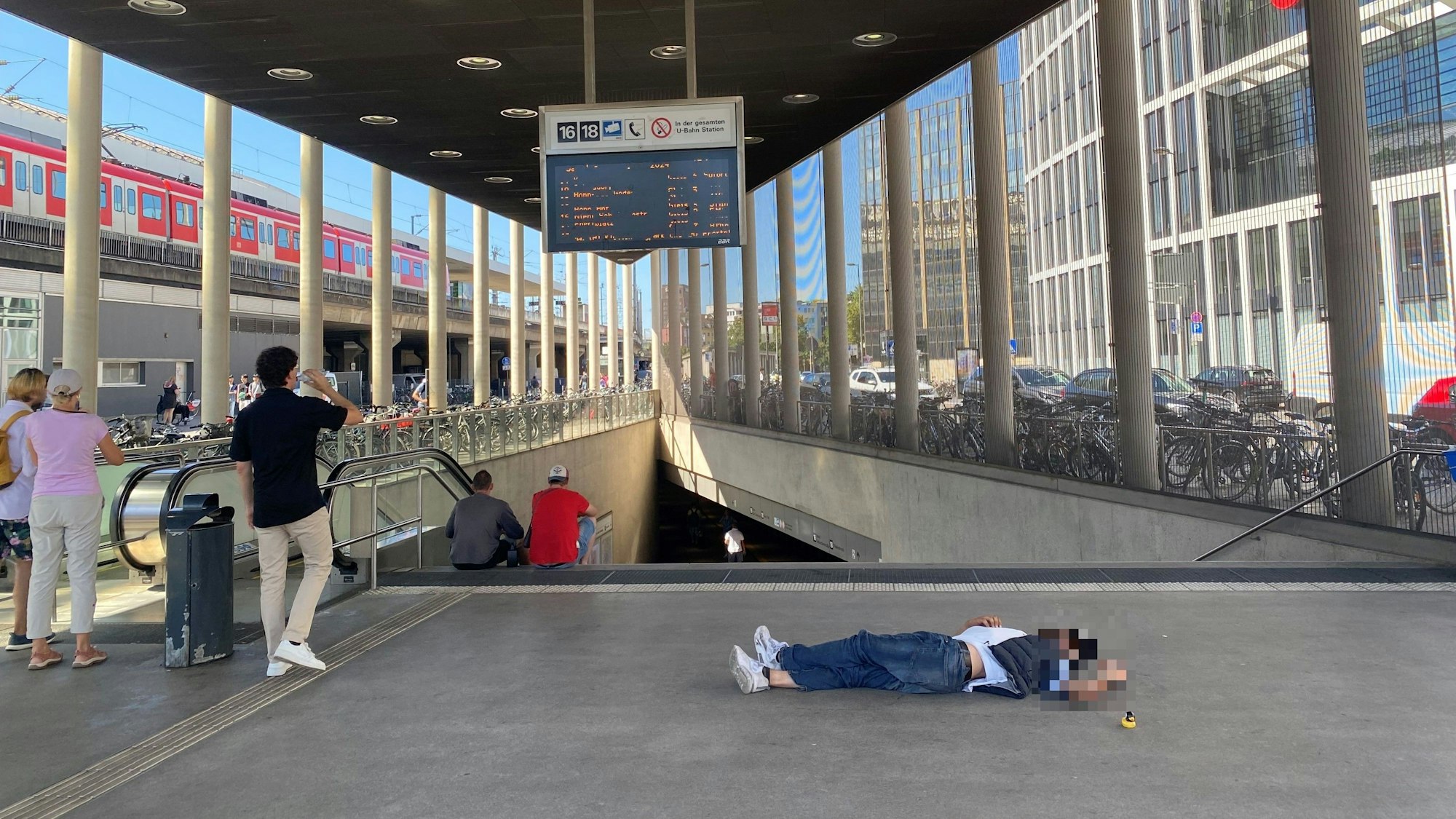 Mann liegt zum Schlafen auf dem Boden am Breslauer Platz in Köln.