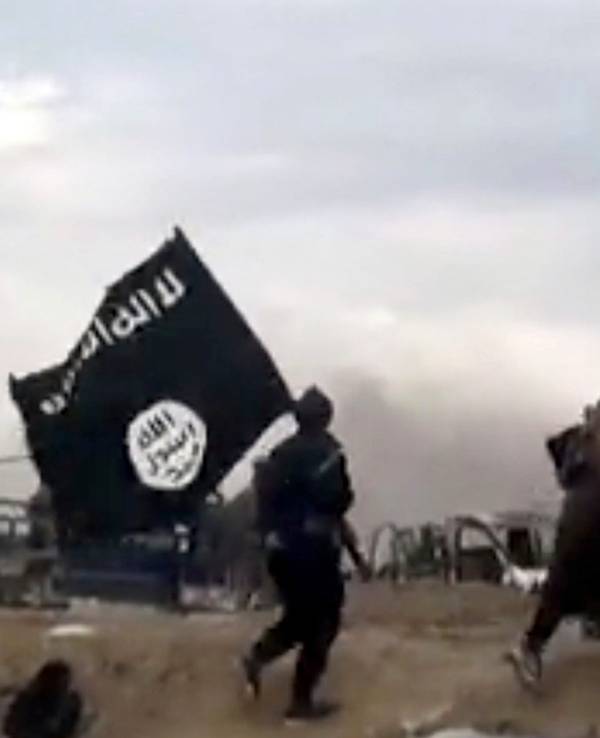 IS-Kämpfer laufen mit einer IS-Flagge durch Baghus in Syrien.