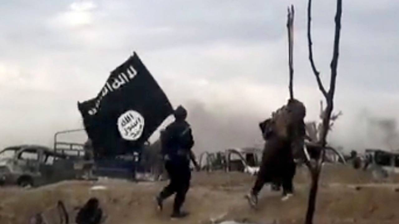 IS-Kämpfer laufen mit einer IS-Flagge durch Baghus in Syrien.