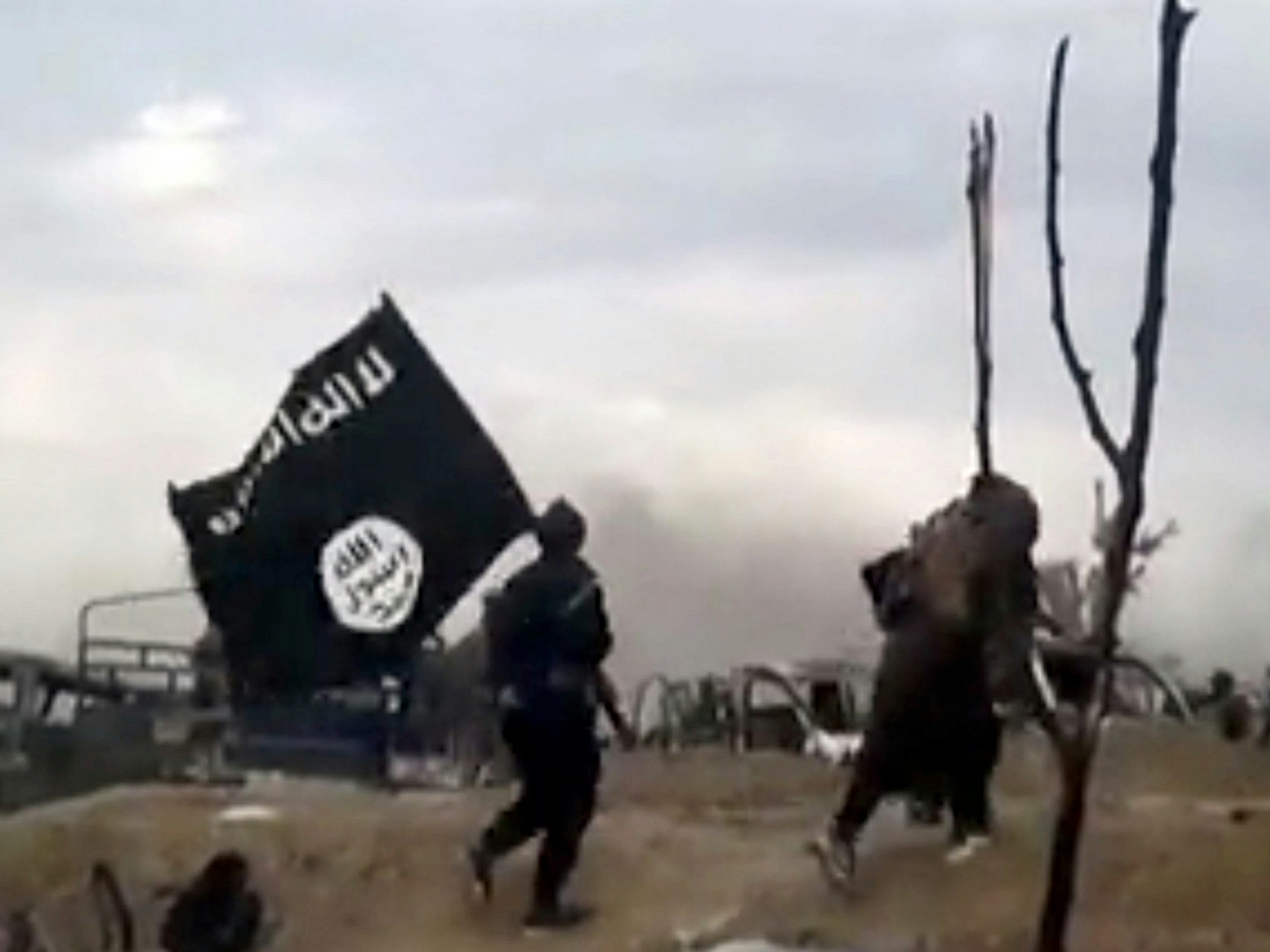 IS-Kämpfer laufen mit einer IS-Flagge.