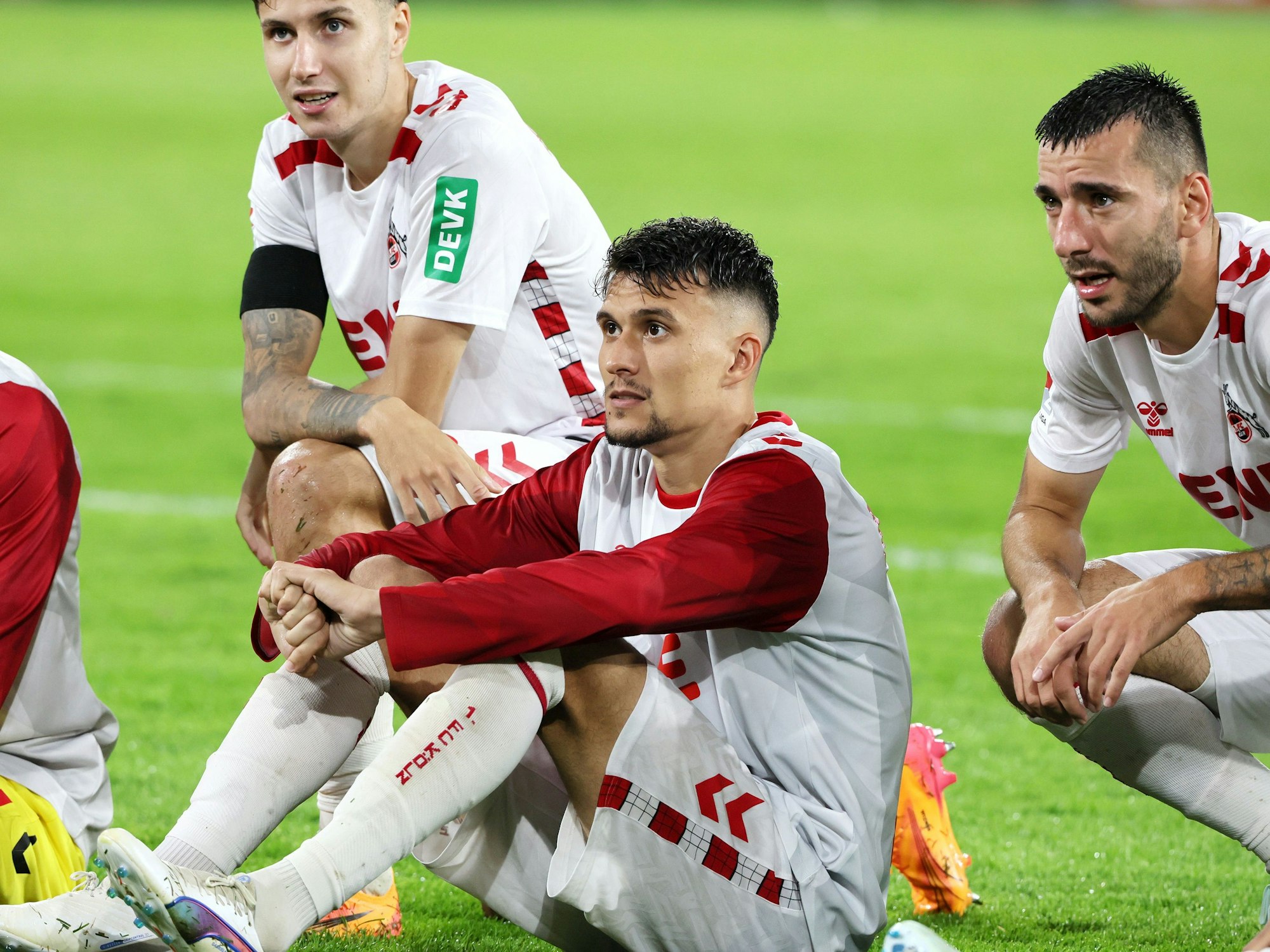 Dejan Ljubicic (1. FC Köln) sitzt auf dem Rasen im Rhein-Energie-Stadion.
